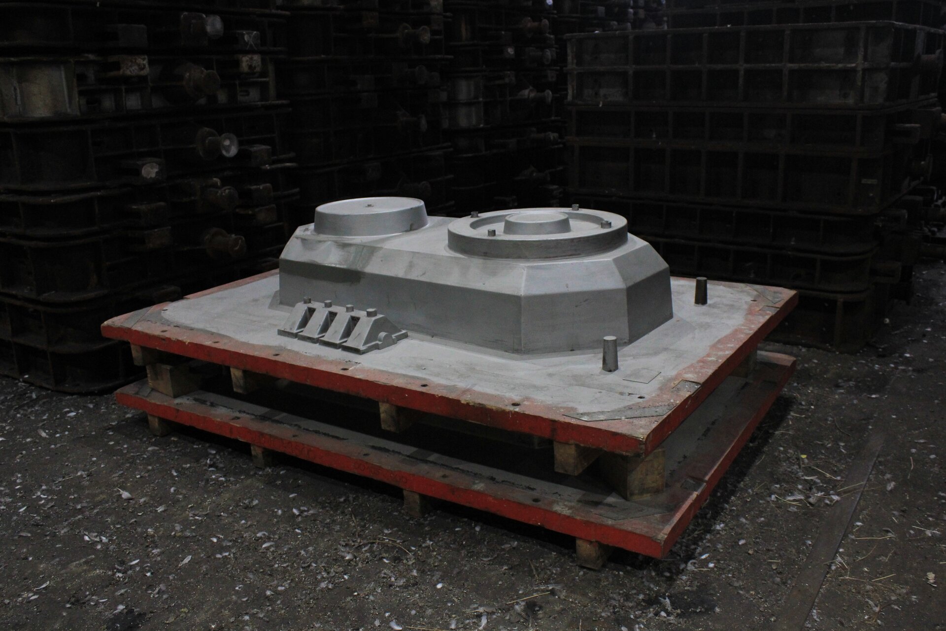 Ilustracja przedstawia płytę modelową. Przypomina ona paletę, na powierzchni której widnieje jednolita bryła, o różnorodnym kształcie. Całość pokryta jest srebrzystą powłoką.