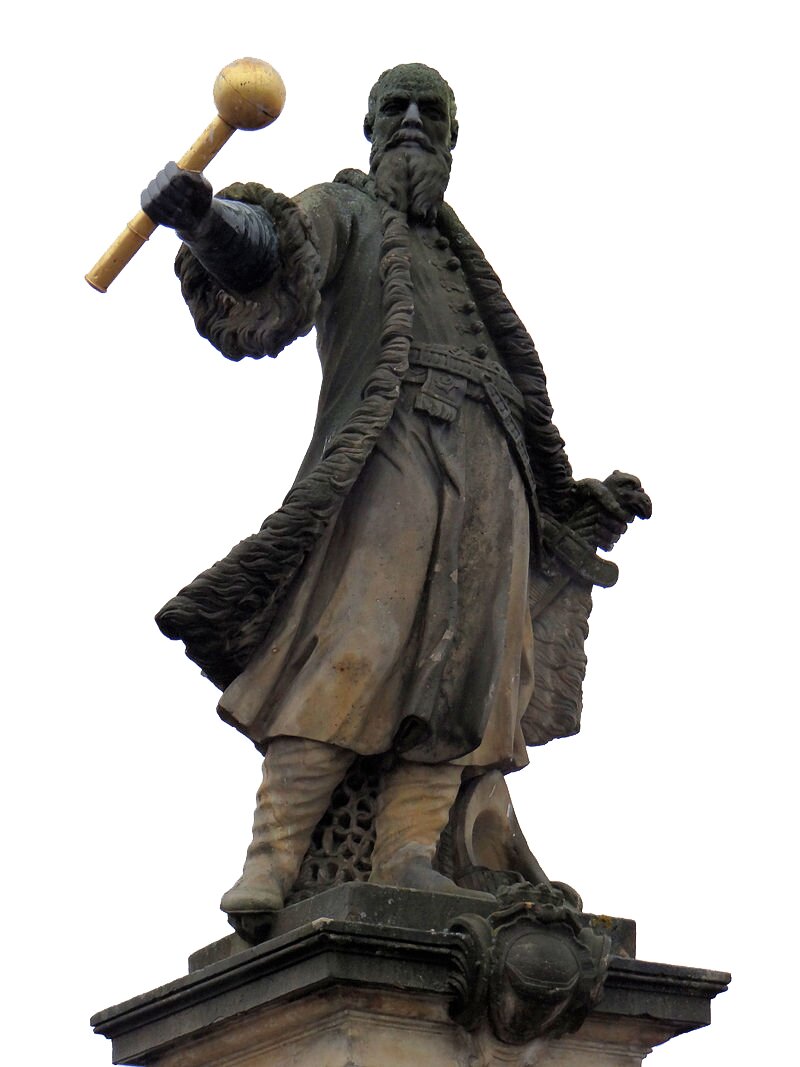 Kliknij żeby powiększyć Zdjęcie przedstawia pomnik Stefana Czarnieckiego. Ma on brodę. Jest ubrany w żupan zapinany na guziki opasany pasem oraz kontusz podbity futrem. Na nogach ma baczmagi. Wspiera się lewą dłonią na szabli. W prawej ręce uniesionej do góry trzyma złotą buławę. Stoi na postumencie.