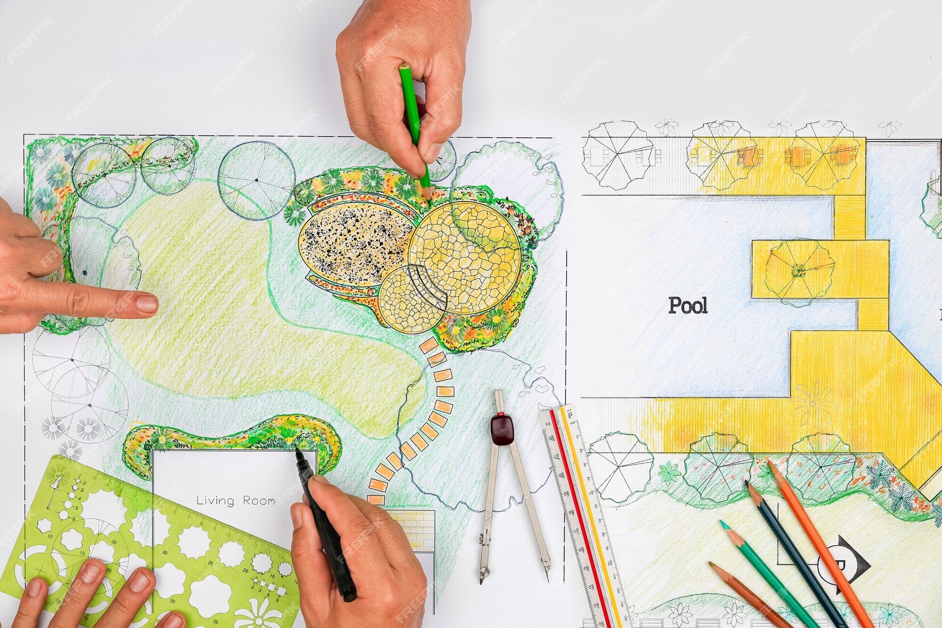 Zdjęcie ukazuje rysunek wykonywany przez kilkoro ludzi. Ukazane zostały jedynie ich pracujące dłonie. Całość rysunku wykonywana jest na dużej, białej kartce, na której wyznaczono prostokąt symbolizujący teren ogrodu. Na ilustracji ogrodu wyznaczono kilka stref. W lewym górnym rogu teren pokryty jest trawą, na której zasadzono rabaty kwietne. Obok znajduje się zaokrąglony kształt symbolizujący oczko wodne, na które wskazuje jedna z dłoni. Następnie umieszczono kolejną kwietną część z elementami wyłożonymi kostką. Nad tą częścią pracuje mężczyzna domalowując detale zieloną kredką. W prawym górnym rogu wyznaczono miejsce na basen, otoczone podestem w kolorze żółtym. Na środku kształtu basenu ukazuje się czarny napis “POOL”. W lewym dolnym rogu ułożona jest duża, zielona, prostokątna linijka z wyciętymi wewnątrz kształtami. Na linijce oparta jest dłoń. Pod linijką znajduje się prostokąt opisany “LIVING ROOM”, przy którym znajduje się rabata, do której kolejna dłoń dodaje detale czarnym markerem. Pozostały teren oznaczony jest zielonymi barwami. Na tej części kartki ułożony został srebrno‑brązowy cyrkiel oraz linijka z czerwoną i żółtą linią. W prawym dolnym rogu na kartce leżą kredki - pomarańczowa, granatowa, zielona oraz brązowa.