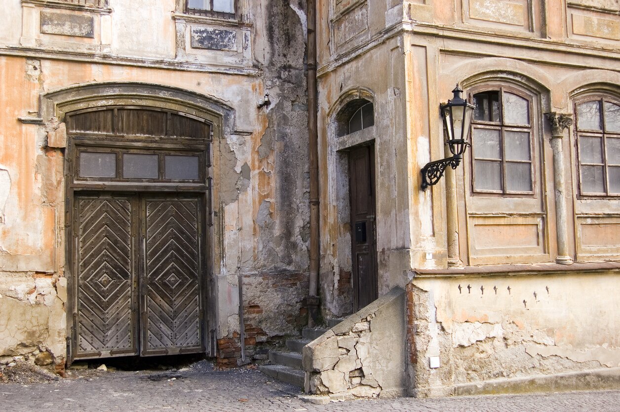 Budynek z uszkodzoną elewacją; widoczne liczne rysy i pęknięcia