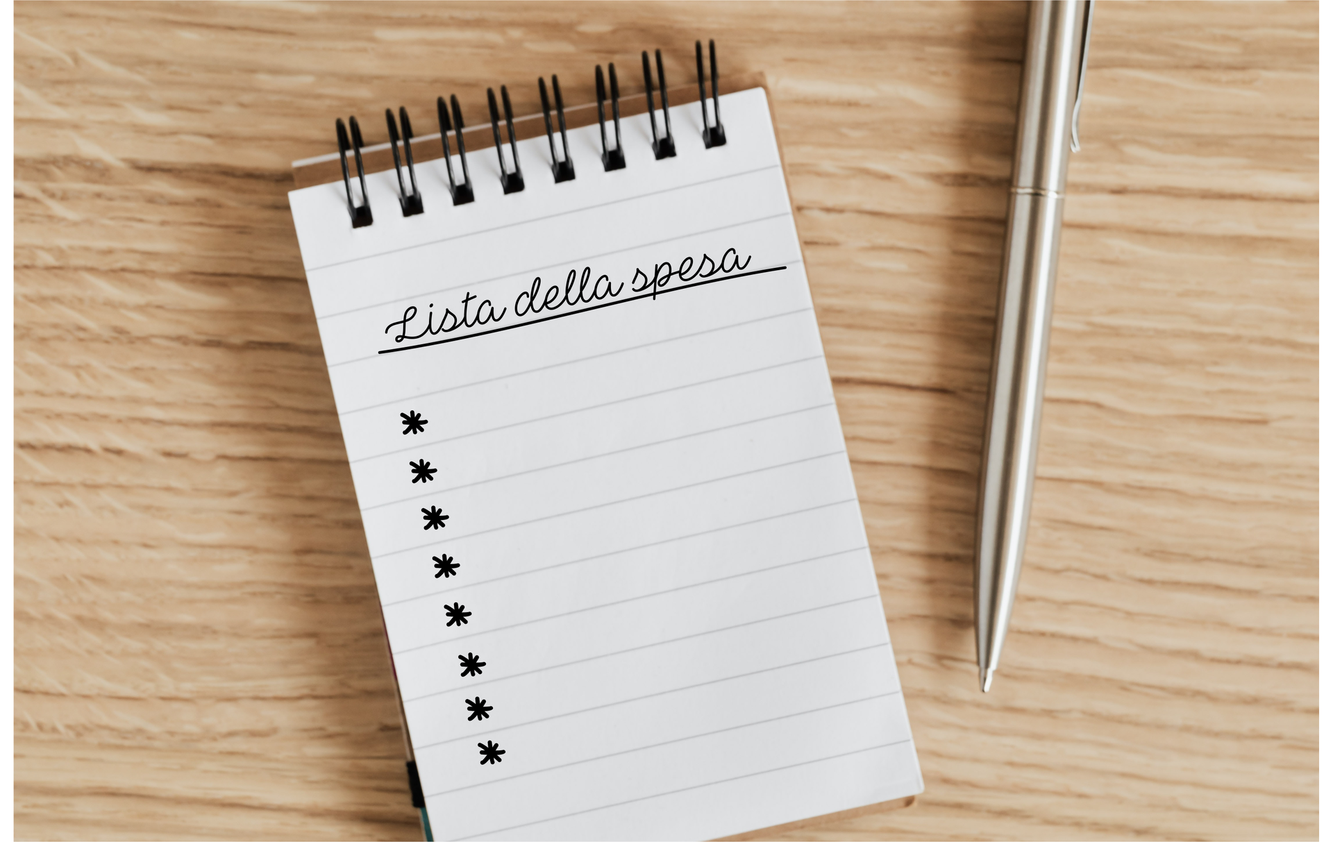 Zdjęcie przedstawia notatnik kołowy i długopis po jego prawej stronie, leżące na stole. Na górze strony widoczny jest zapis: Lista della spessa. Poniżej narysowano kilka gwiazdek, jako kolejne punkty listy. 