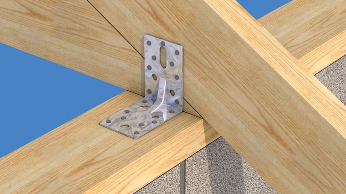 Na zdjęciu widoczny punkt styku dwóch drewnianych belek, jedna jest ułożona na płasko, druga zachodzi na nią po skosie. Punkt styku jest przymocowany płaską metalową blaszką z wypustkami, której jedna część przytwierdzona została do jednej belki, a druga do drugiej. Blaszka tworzy kąt prosty.