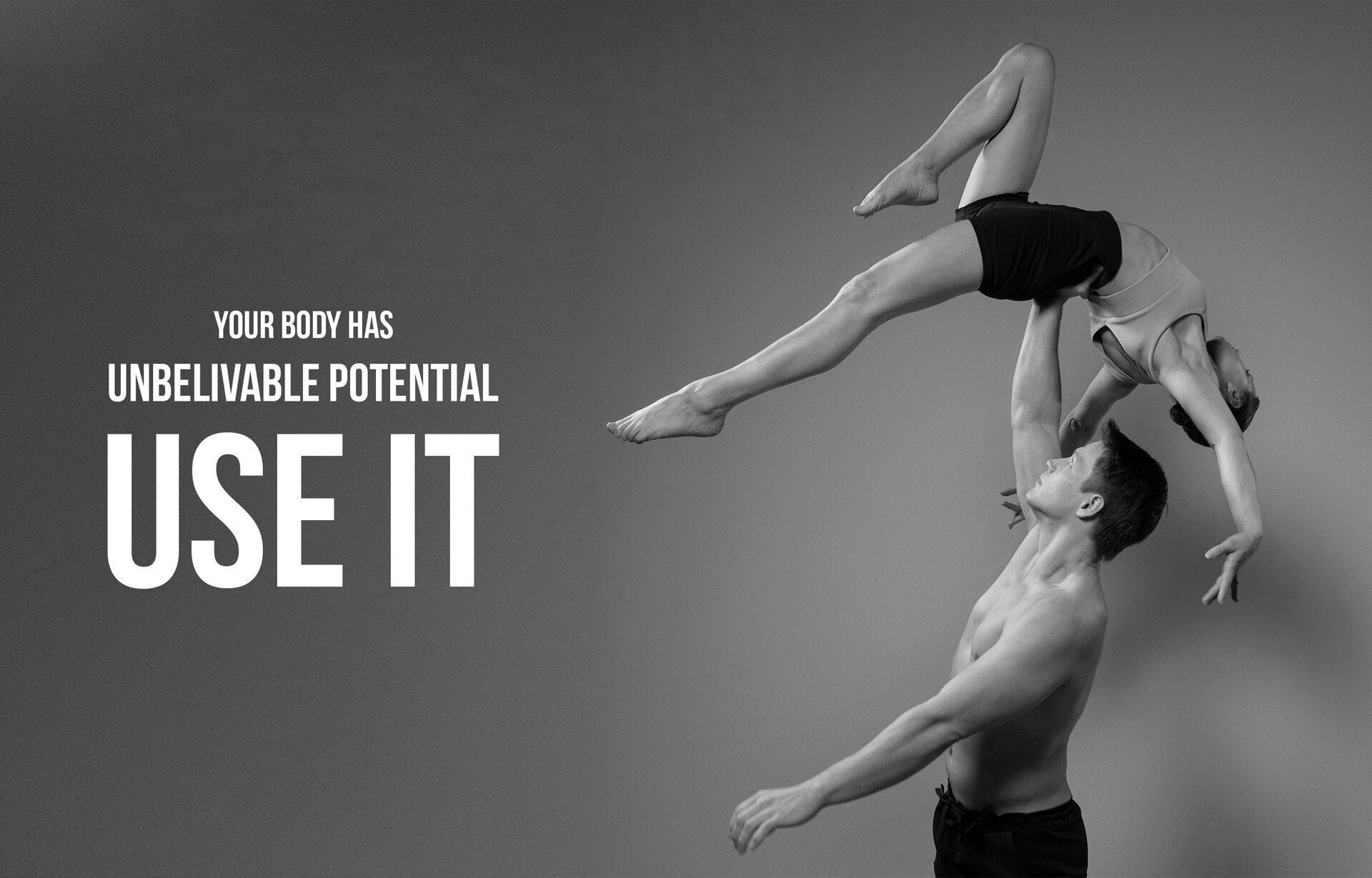 Czarno‑białe zdjęcie przedstawia parę młodych ludzi, którzy wykonują akrobację gimnastyczną. Mężczyzna ma nagi tors i ciemne spodnie, stojąc trzyma prawą ręka wyprostowaną w górze, na której leży kobieta. Kobieta jest ubrana w czarne obcisłe spodenki i jasny, krótki top. Ma ciało wygięte w łuk, ręce opuszczone w dół, prawą nogę zgiętą w kolanie i podciągniętą do góry, a lewą nogę wyprostowaną. Na lewo od nich widoczny jest napis w języku angielskim: YOUR BODY HAS UNBELIEVABLE POTENTIAL - USE IT.