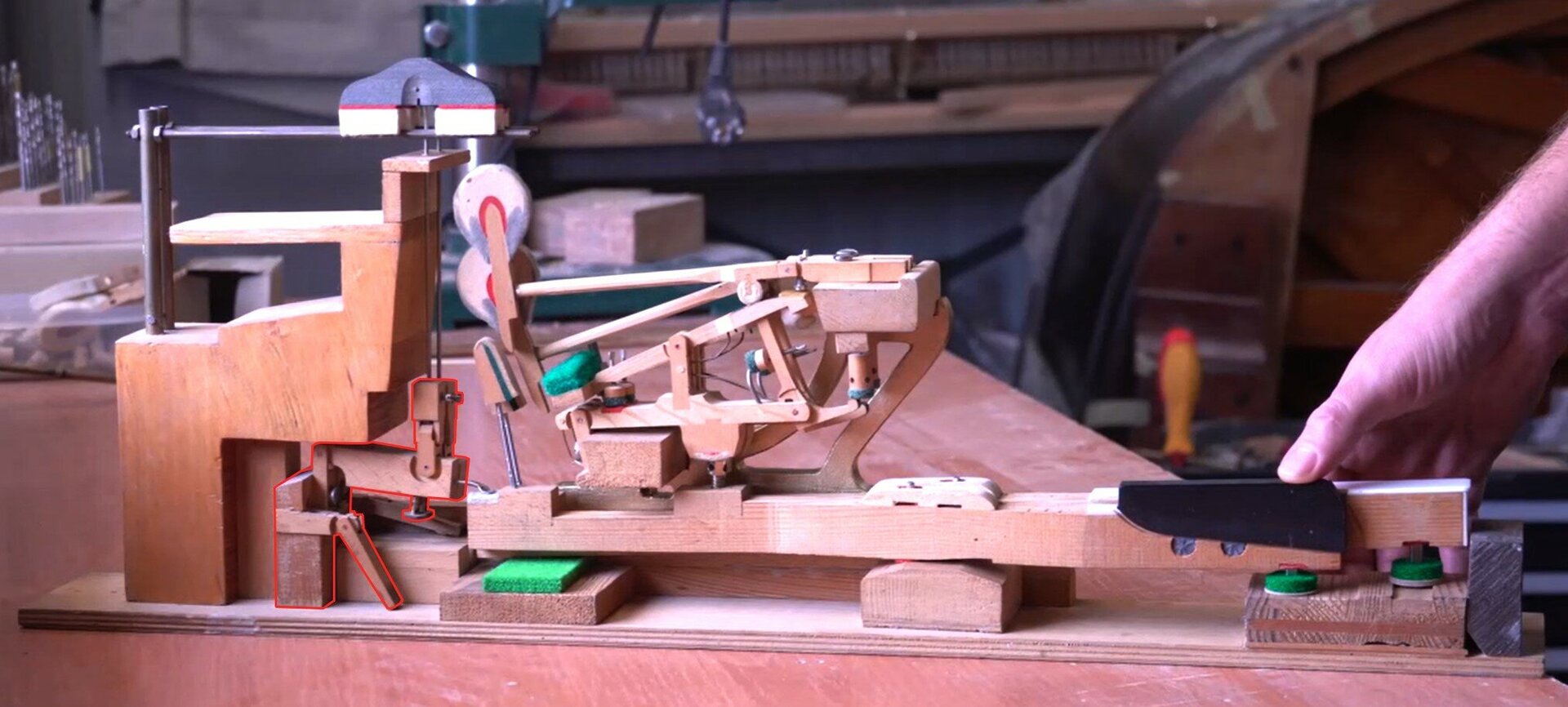 Zdjęcie przedstawia podzespół mechanizmu pianinowego lub fortepianowego jakim jest tłumik. Element został zaznaczony czerwoną obwódką, a dodatkowo pozostałe elementy są w odcieniach szarości dla lepszego uwidocznienia.