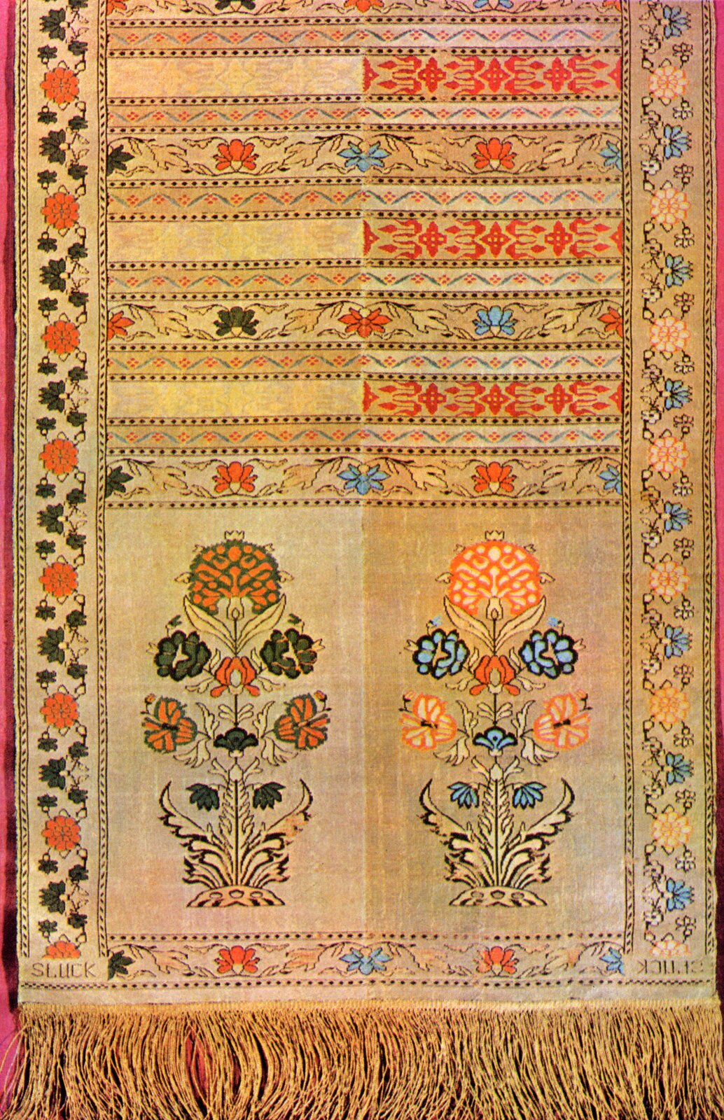 Zorientowana pionowo fotografia barwna przedstawiająca jedną ze stron czterostronnego słuckiego pasa kontuszowego. Pasy czterostronne uzyskiwano w ten sposób, że strona prawa i lewa były podzielone wzdłuż na dwie połowy, które różniły się kolorystyką, a nieraz wzorem. Taka budowa pozwalała na to, by jeden pas, który składano wzdłuż na pół, mógł być stosowany w czterech wariantach. Zakończenie pasa, zwykle o dużym wzorze, zwano głową i czasem ozdabiano frędzlami; środkowe pola, najczęściej o wzorze drobnym – wciążem. Poprzeczne paski dzielące wciąż nazywano pólkami, zewnętrzny, obramiający ornament, bordiura, to szlaczek. Pasy składano wzdłuż, przy czym jedna strona, bardziej ozdobna, była noszona w dni świąteczne i podczas uroczystości, a druga, skromniejsza, na co dzień. Często do pasa zawieszano paski do podwieszania pochwy szabli – rapcie. Na fotografii głowa zakończona frędzlami znajduje się u dołu. Zawiera ona motyw dwóch wpisanych w prostokąt ukwieconych krzaczków o splecionych symetrycznie łodygach, wyrastających z uciętych pni posadowionych na kopczykach. Prawa strona na tle, z ugrowo‑złotym wzorem; kwiaty czerwone i niebieskie. Po lewej beżowo‑srebrne tło z jaśniejszym wzorem, kwiaty czerwone i szare z łodygami. Środek w poprzeczne pólka, rozdzielone szlaczkami z drobnych rombów. W pólkach wciąża powtarzający się motyw wici kwiatowej. Kwiaty powtarzają kolor odpowiednio do ukazanego na kwiatach głowy. Po lewej mniej ozdobnej stronie co drugie pólko puste, po prawej wypełnione czerwonym ornamentem. Szlaczek po prawej w niebieskie i białe kwiatki na wici, a po lewej w szare i czerwone. U dołu szlaczki kończą napisy SŁUCK.