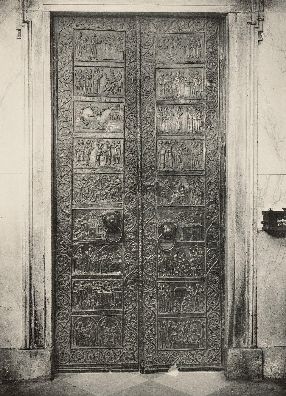 Ilustracja o kształcie pionowego prostokąta przedstawia czarno‑białą fotografię Drzwi gnieźnieńskie. Zabytek podzielony jest na 18 prostokątnych kwater, po 9 w każdej połowie. Sceny zamieszczone w kwaterach przedstawiają motywy z życia św. Wojciecha ułożone chronologicznie. Należy je czytać, rozpoczynając od lewej strony ku górze, następnie od prawej ku dołowi. Wokół każdego skrzydła znajduje się dekoracyjna bordiura z motywami roślinnymi, zwierzęcymi i alegorycznymi. W czwartych kwaterach od dołu znajdują się kołaty z głowami lwów.  