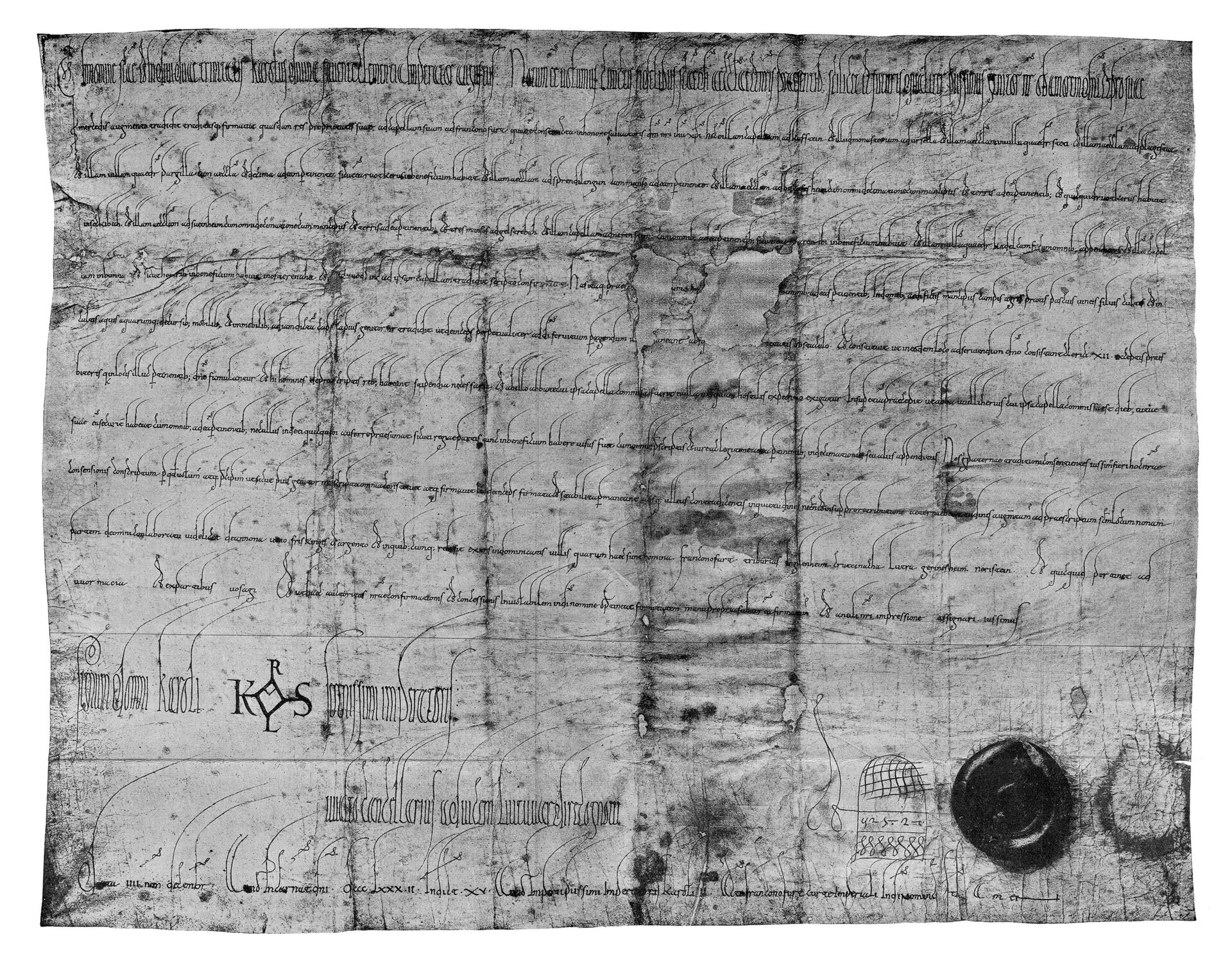 Czarno‑biała fotografia, przedstawiająca opieczętowany dokument z cesarskim podpisem. Tekst zapisany minuskułą karolińską.