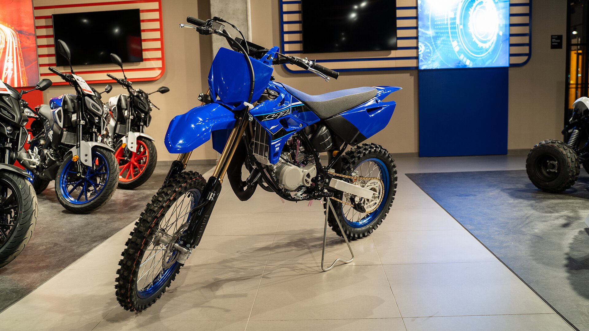 Zdjęcie przedstawia motocykl o lekkiej ramie. Motocykl jest wąski. Ma głęboki bieżnik na oponach. Pojazd ma niebieską ramę.  