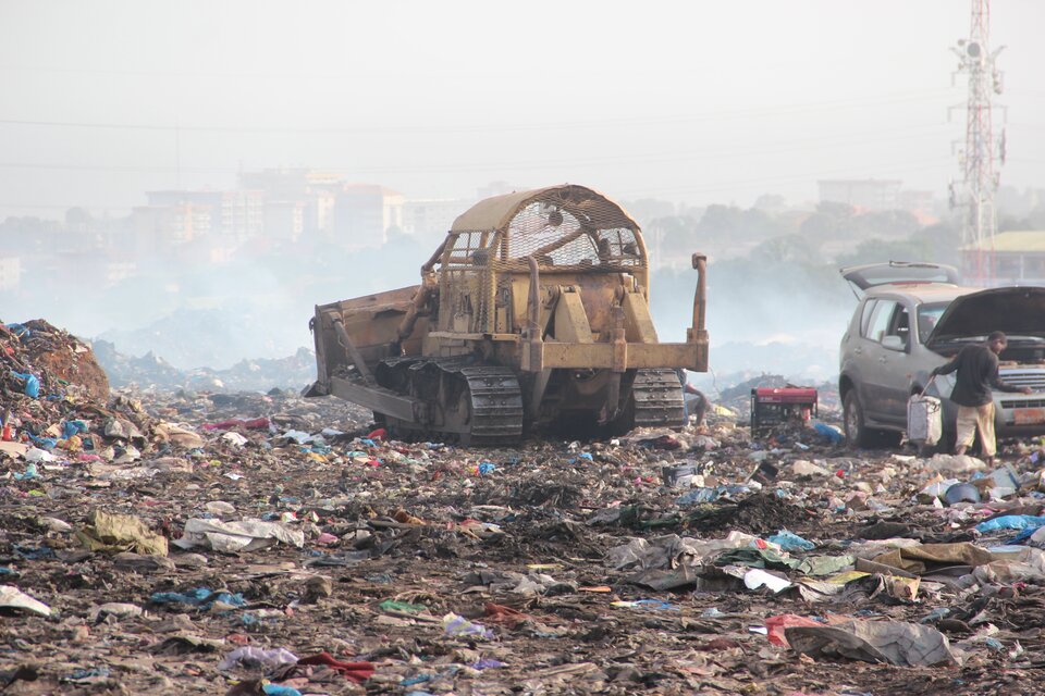 Zdjęcie przedstawia wysypisko śmieci. Na wysypisku znajduje się spychacz. 