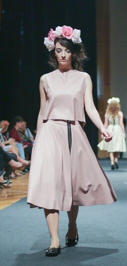 Zdjęcie przedstawia modelkę prezentującą beżowy komplet składający się z bluzki oraz spódnicy.