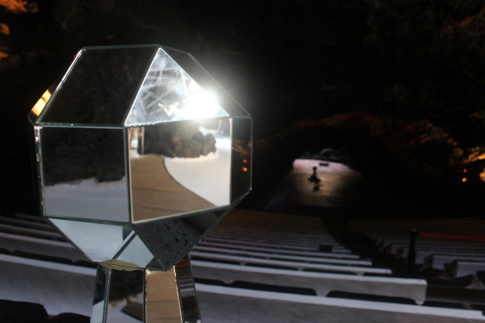 Zdjęcie przedstawia błyszczącą bryłę jako złożenie kilku luster oraz „zajączka”, czyli promienia światła odbitego w zwierciadle. Tło ciemne. W lustrach widać zarysy odbitych przedmiotów.