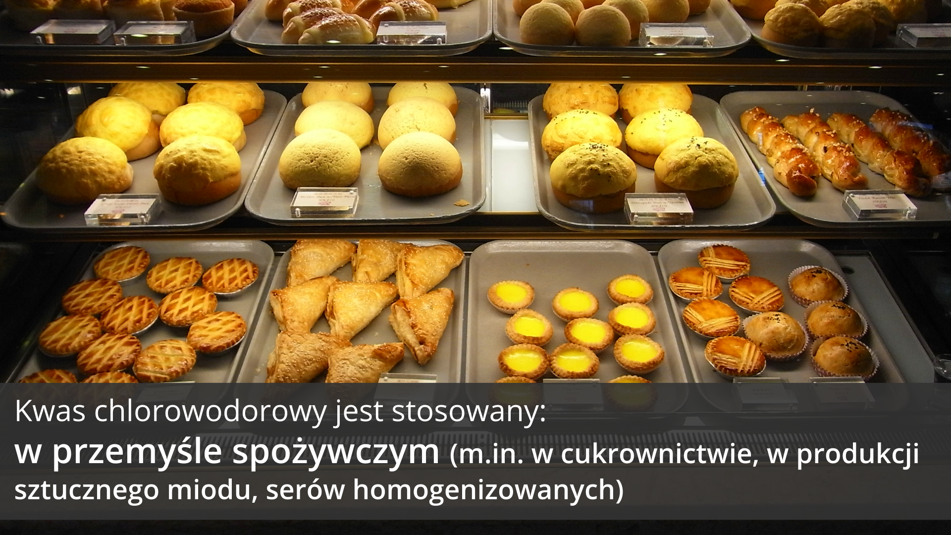 Piąta ilustracja galerii przedstawia zdjęcie lady cukierni lub piekarni. Na tacach ułożonych w trzech mieszczących się nad sobą rzędach ustawione są rozmaite wyroby cukiernicze: ciastka, słodkie bułki, babeczki, ciastka kruche i drożdżowe. Na każdej tacy znajduje się tabliczka z ceną. Na tle obrazka, w dolnej części ilustracji, znajduje się ciemnoszary pasek, na którym umieszczono jasny napis: Kwas chlorowodorowy jest stosowany w przemyśle spożywczym, między innymi w cukrownictwie, w produkcji sztucznego miodu i serów homogenizowanych.