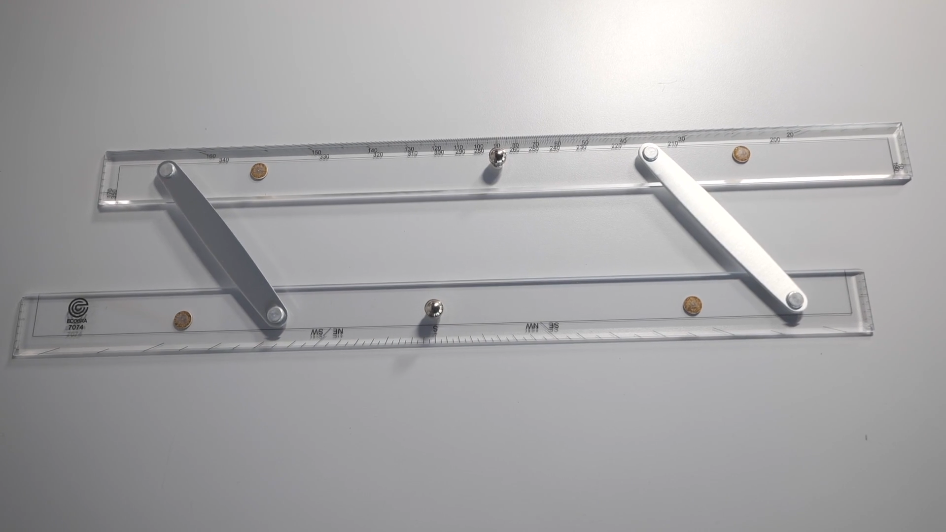 Zdjęcie przedstawia liniał równoległy. To narzędzie składające się z dwóch linijek połączonych ze sobą. Linijki można przemieszczać w stosunku do siebie.