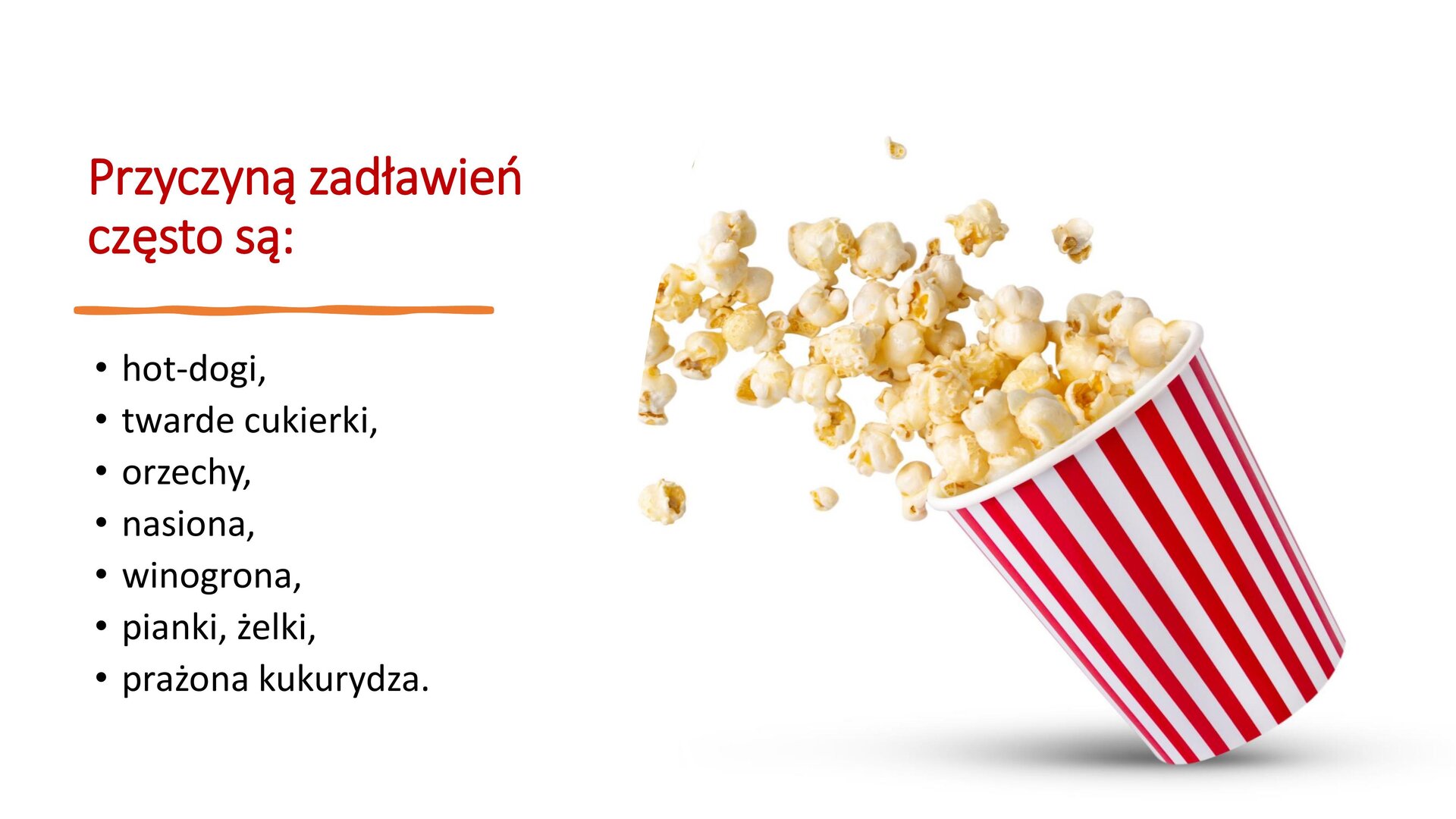 Biały slajd, który przedstawia tekst oraz zdjęcie. Z prawej strony slajdu pudełko w biało‑czerwone pionowe pasy, z którego wysypuje się popcorn. Z lewej strony slajdu tekst: „Przyczyną zadławień często są: hot‑dogi, twarde cukierki, orzechy, nasiona, winogrona, pianki, żelki, prażona kukurydza”.
