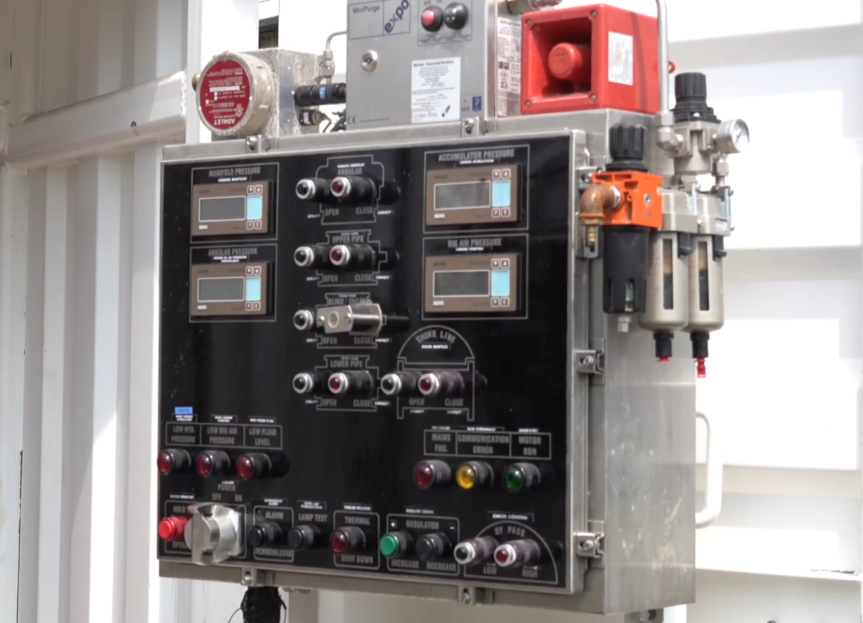 Na zdjęciu widoczna jest sterowania zabezpieczenia przeciwerupcyjnego. Sterownia jest w fomie prostopadłościennej skrzynki  wykonanej z metalowej obudowy. Na przodzie skrzyni znajdują się przełącznik, oraz cztery niewielkie ekrany. Na dole sterowni widać dziewięć przełączników. Powyżej po każdej stronie znajduje się po trzy kolorowe guziki. W środkowej części sterowni widocznych jest osiem przyciski są rozłożone po cztery w dwóch kolumnach. Obok przycisków, po obu stronach znajdują się dwa niewielkie ekrany. Nad ekranami z prawej strony znajdują się dodatkowe przyciski. Nad każdym przyciskiem umieszczona jest niewielka tabliczka z nazwą.Na boku obudowy znajduje się urządzenie z okrągłym wskaźnikiem. Na górze obudowy widoczne są trzy sześciennej urządzenia. Urządzenie po lewej przypomina wodomierz. Urządzenie po środku ma dwa przyciski. Zielony i Czerwony. Urządzenie po prawej przypomina sześcian z wyciętą ścianą boczną. W jej miejscy znajduje się poziomy walec.Poniżej zdjęcia w prawym dolnym rogu widoczny jest przycisk odtwarzania. Tekst nagrania jest zgodny z tytułem zdjęcia.