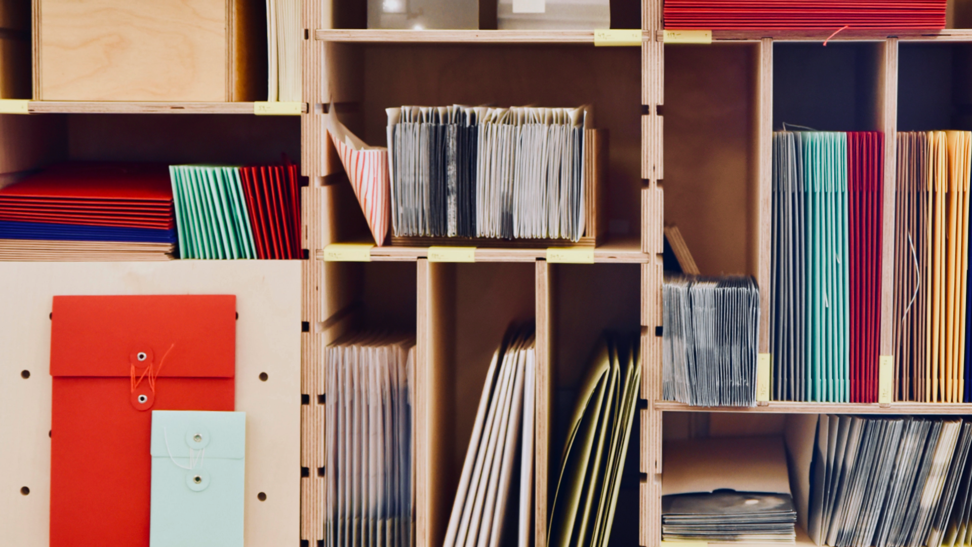 Zdjęcie przedstawia półki w sklepie z artykułami papierniczymi. Na półkach widoczne są różnego rodzaju teczki, skoroszyty.