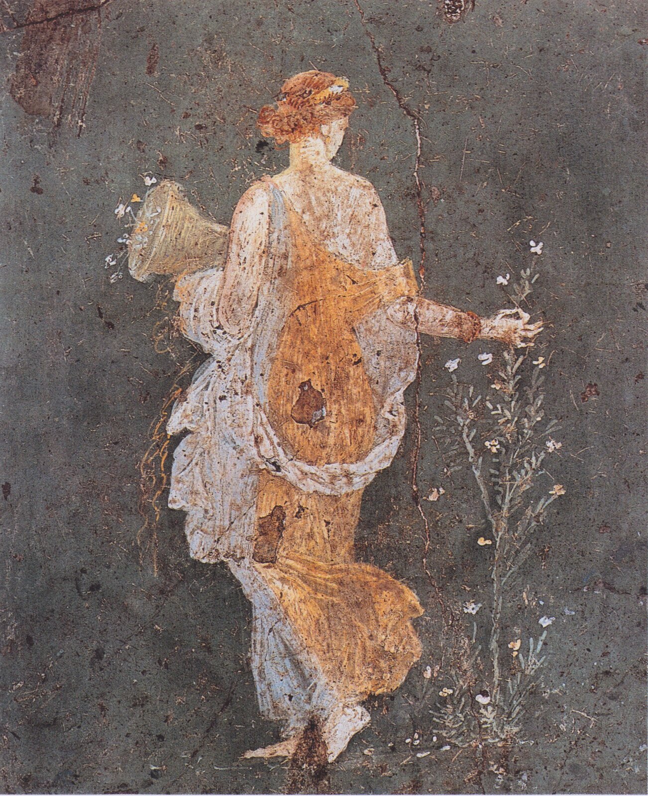 Fresk nieznanego autora przedstawia Florę – młodą kobietę, która przedstawiona jest tyłem do widza, ma spięte długie rude włosy, biało-brązową suknię. W jednej dłoni trzyma pojemnik, a drugą sięga po kwiat rośliny, która z wyglądu przypomina popularny chwast. Fresk został stworzony na ciemnej ścianie. 
