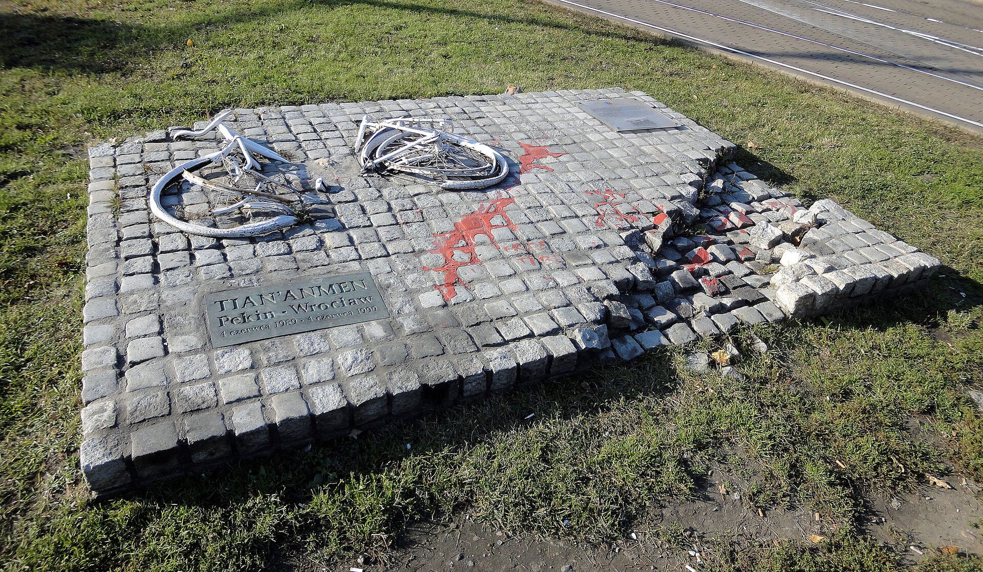 Na zdjęciu znajduje się replika zniszczonego w 1989 roku przez komunistów pomnika we Wrocławiu poświęconego masakrze na placu Tian’anmen z 4 czerwca 1989 roku. Na pomniku położony jest przepołowiony na pół biały rower. W lewym dolnym rogu pomnika nie ma części kostki. Na pomniku jest rozlana czerwona ciecz przypominająca krew. W lewym dolnym rogu umieszczono tablicę z napisem:   TIAN'ANMEN Pekin - Wrocław, 4 czerwca 1989 - 4 czerwca 1999.
