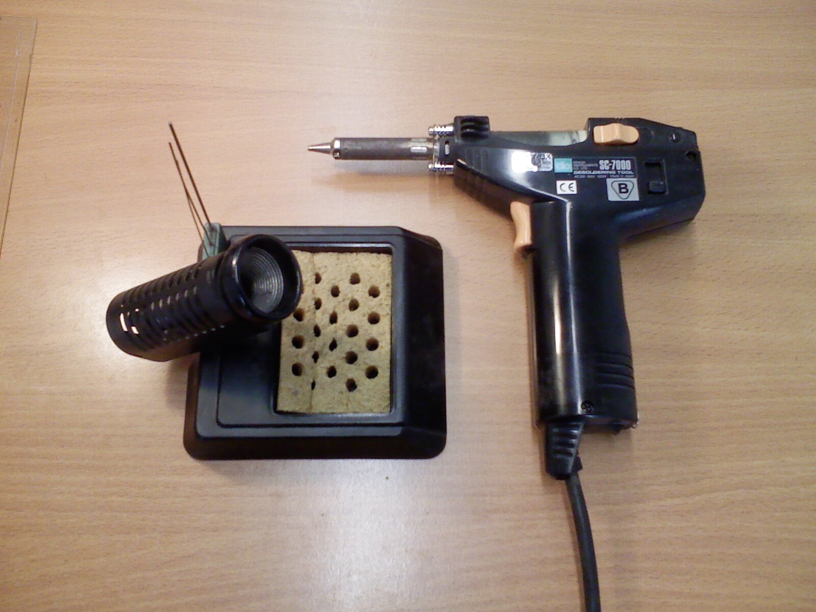 Zdjęcie przedstawia lutownicę pistoletową wraz ze stojakiem z gąbką.