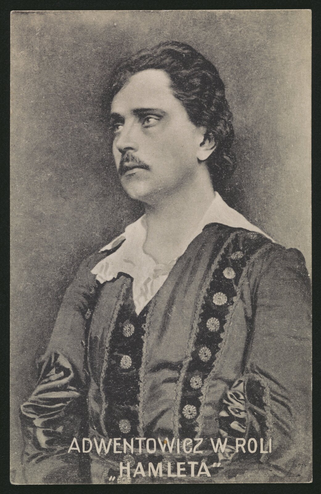 Czarno-biała fotografia przedstawia zamyślonego mężczyznę z wąsikiem. Mężczyzna ma bujne włosy zaczesane do tyłu i wysokie czoło. Ubrany jest w szatę z białym kołnierzem. Na dole napis "Adwentowicz w roli Hamleta".