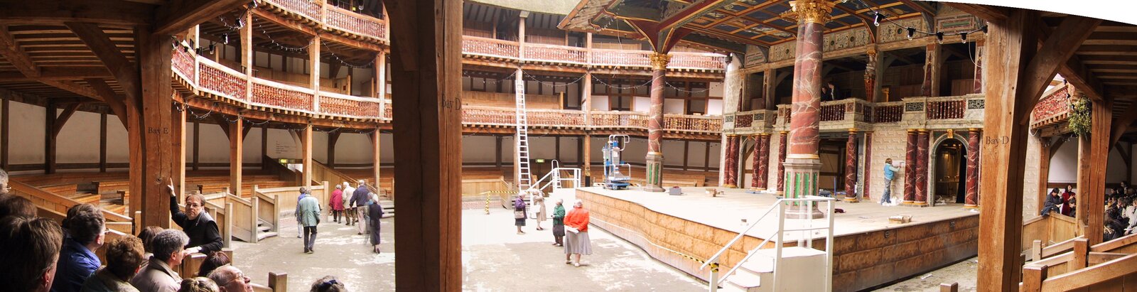 Na zdjęciu widzimy wnętrze teatru. Z prawej strony podwyższona scena z dachem wspartym dwiema kamiennymi kolumnami. Wokół sceny widzimy dwa piętra z miejscami dla widowni. Jest to drewniana konstrukcja wsparta licznymi kolumnami. Gdzieniegdzie widać oglądających pomieszczenie ludzi.