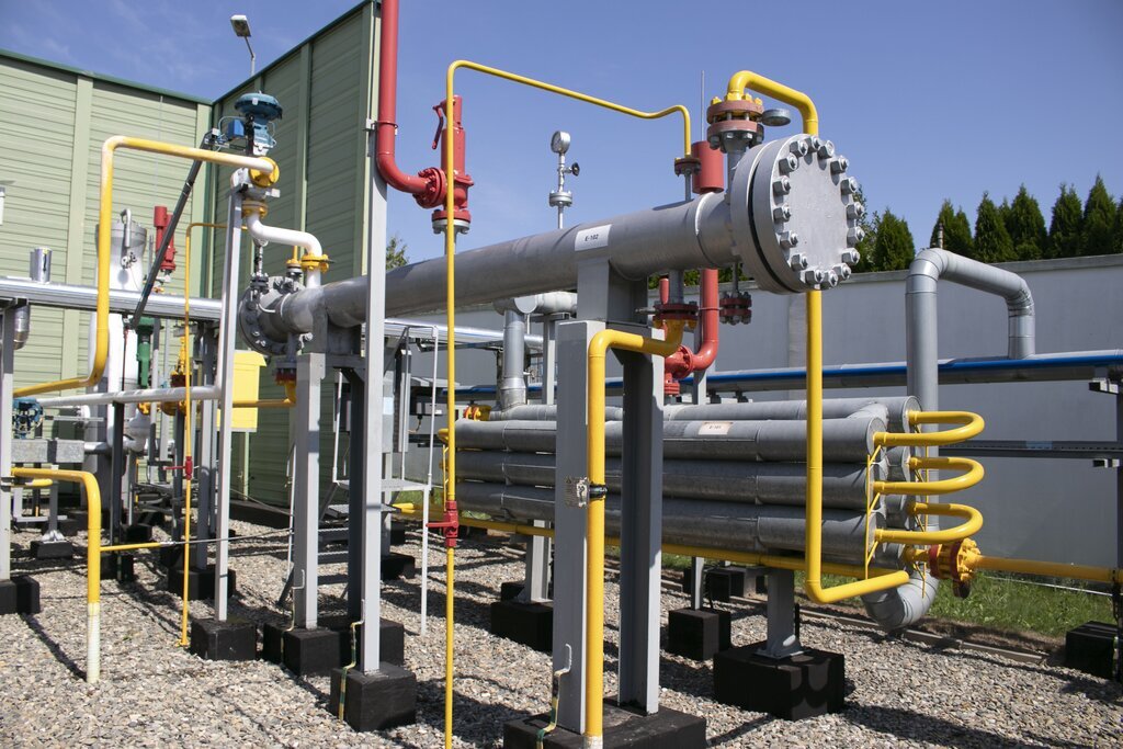 Na ekranie widoczny jest wymiennik ciepła. Wymiennik ciepła jest urządzeniem umożliwiającym wymianę ciepła pomiędzy płynami o różnej temperaturze. Wymiana ciepła zachodzi poprzez zjawiska konwekcji i przewodzenia.Widoczny na zdjęciu wymiennik składa się z długiego cylindra w orientacji poziomej pogrubionego na obu końcach. Znajduje się on na dwóch podstawach. Za wymiennikiem znajduje się siedem cylindrów w orientacji poziomej połączonych ze sobą za pomocą żółtych rur. Do wymiennika ciepła poprowadzona jest żółta rura wychodząca z ziemi. Nad wymiennikiem ciepła znajduje się ciśnieniomierz. Z lewej strony i w oddali znajduje się sieć rur różnego przeznaczenia.