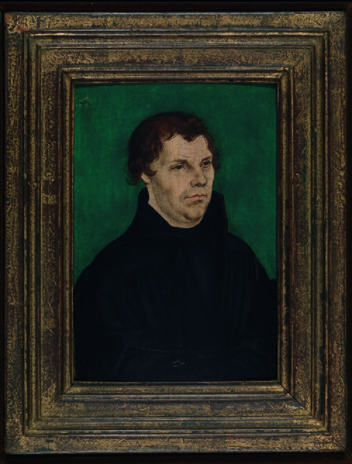 Obraz - portret mężczyzny w dojrzałym wieku. Mężczyzna ma ciemne, krótkie włosy. Ubrany jest w czarny strój. Portret jest w masywnej ramie.  