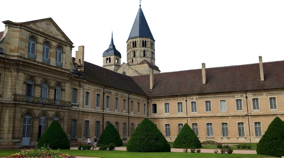 Zdjęcie przedstawia piętrowy pałac z widoczną wieżą, tuż za nim. Przed pałacem ogród. 