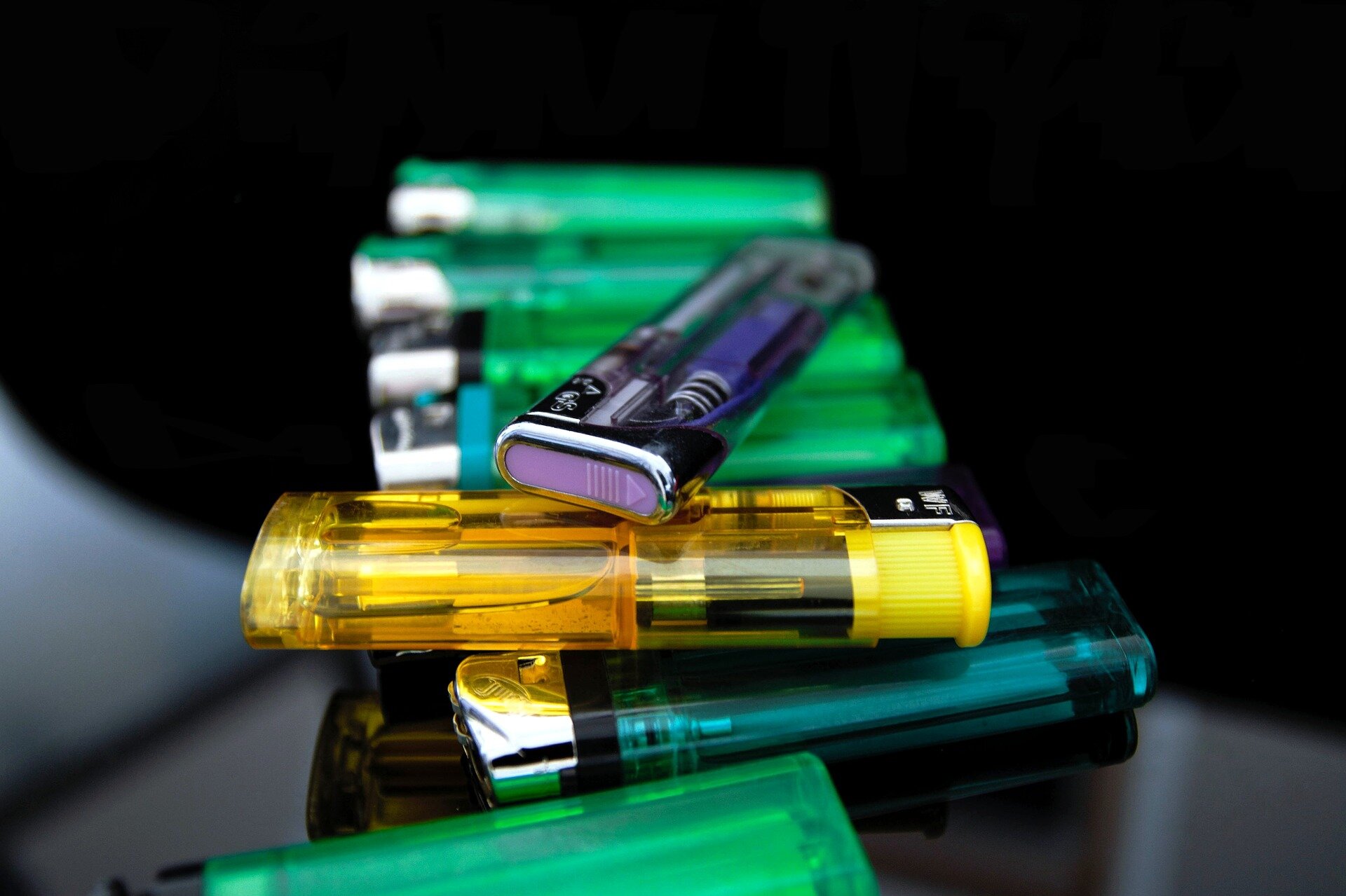 Zdjęcie przestawia stos zapalniczek piezoelektrycznych, plastikowych w różnych kolorach.