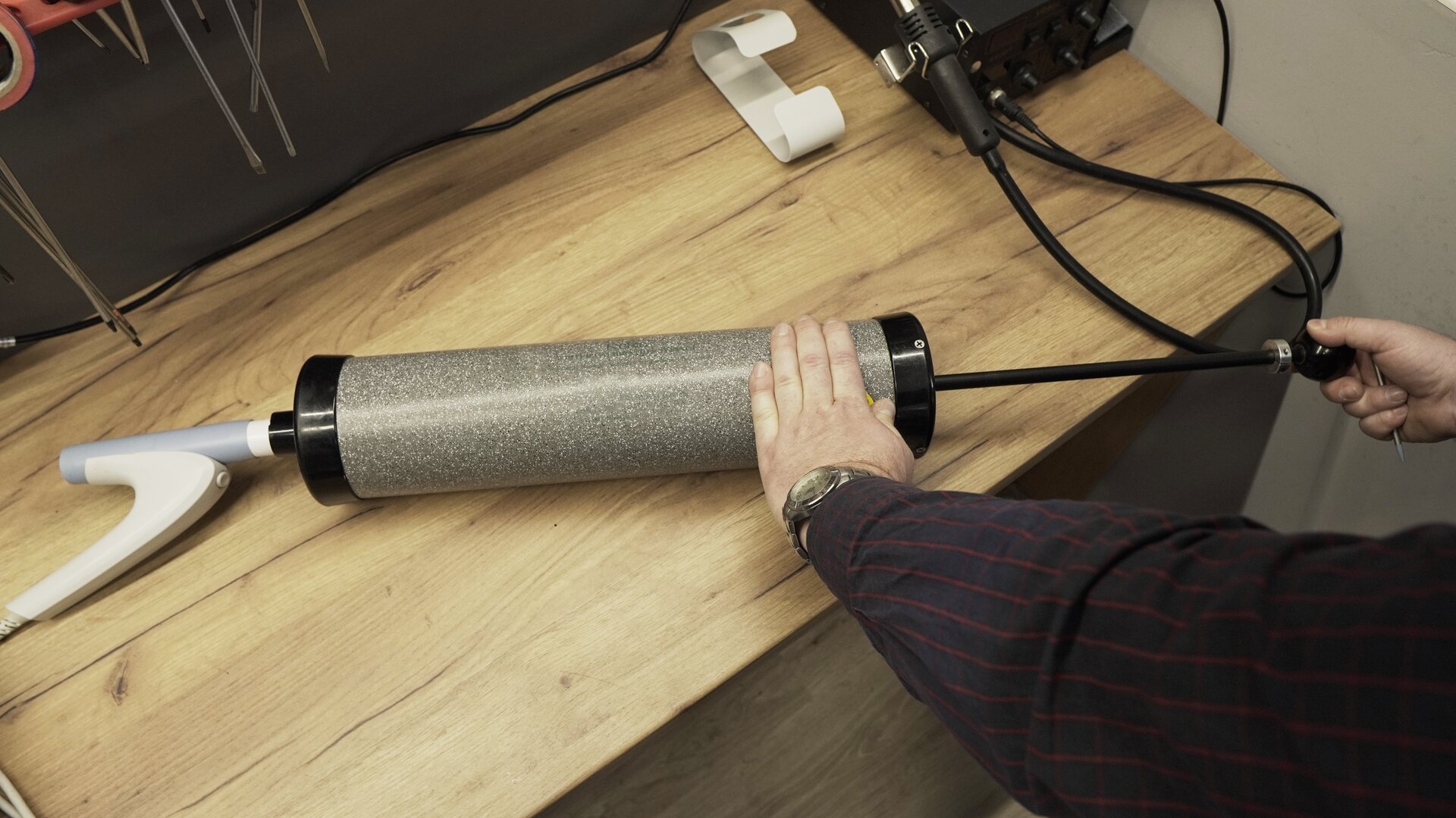 Na zdjęciu technik cewą ręką przytrzymuje tubę pompy, druga znajduje się na rękojeści wysuniętego tłoka.
