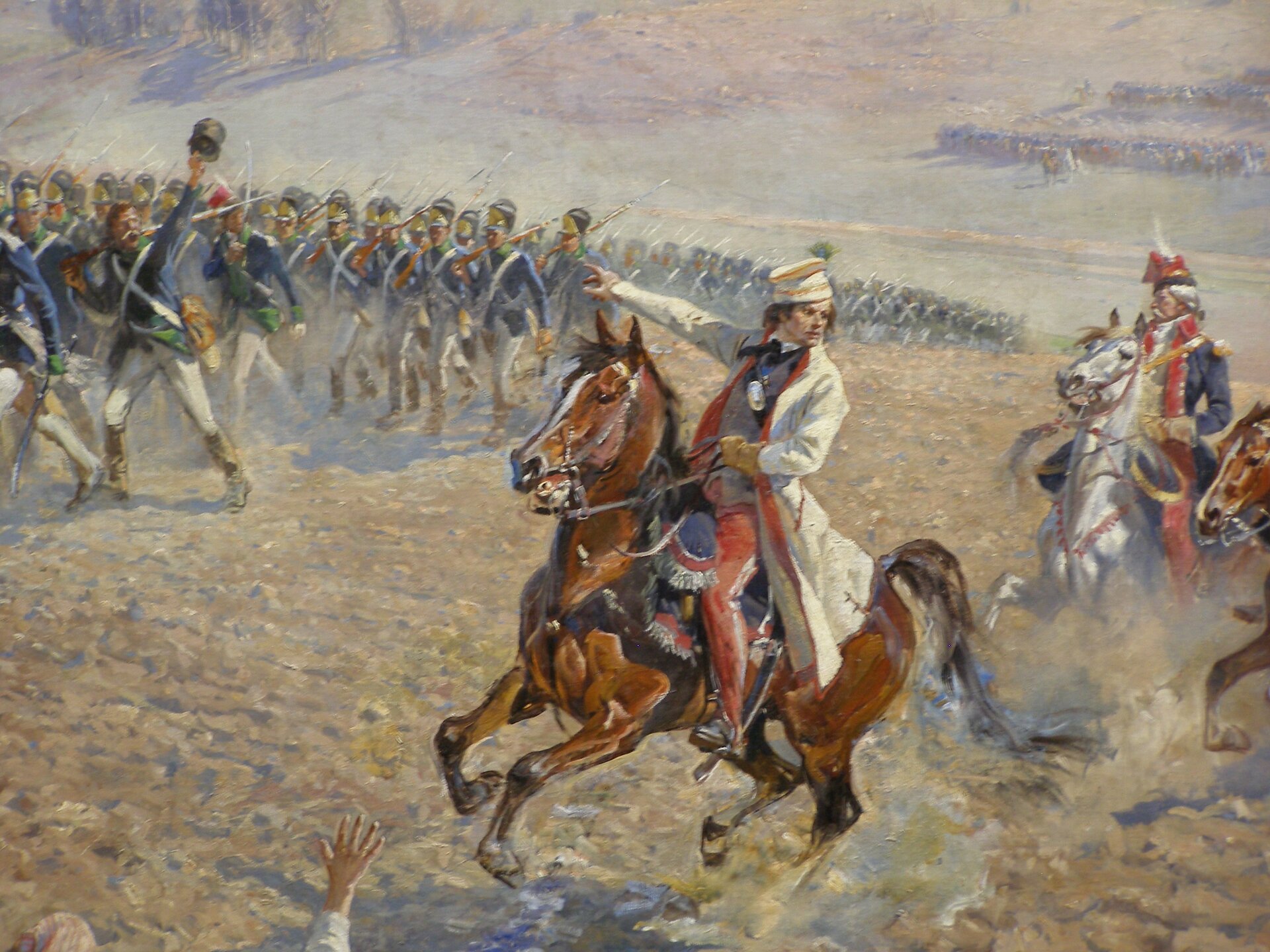 Na obrazie mężczyzna jadący na koniu. Jest ubrany w jasny strój, prawą dłonią wskazuje maszerujących żołnierzy z długą bronią i bagnetami. Za nim żołnierz na koniu z długą czapką i w mundurze. 