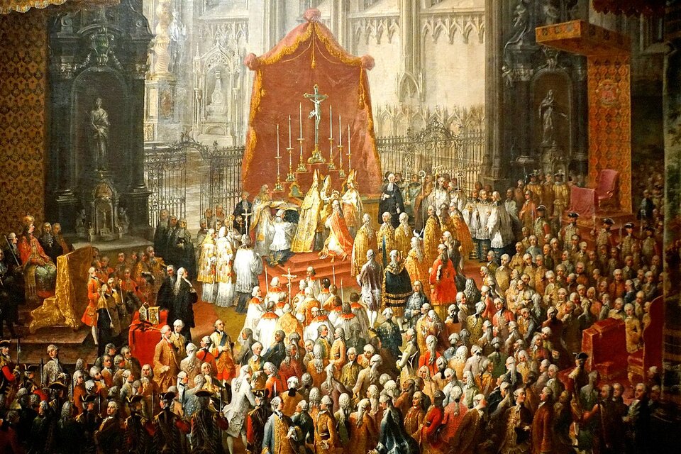 Obraz przedstawia wnętrze ogromnego kościoła. Pod ołtarzem dokonywany jest przez duchownych akt koronacji Józefa II na króla rzymskiego. Scenie tej przypatruje się licznie zgromadzona w kościele arystokracja i duchowni. Król klęczy pod ołtarzem, a papież w typowych dla siebie szatach i papieskiej piusce nakłada królowi koronę na głowę. Nad ołtarzem naciągnięte jest ogromne czerwone płótno, wokół umieszczono wysokie świece na świecznikach. Ściany kościoła są zdobione rzeźbami.  