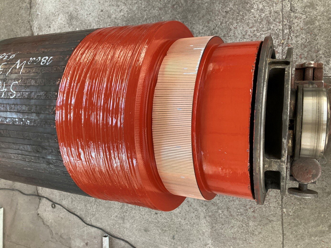 Zdjęcie przedstawia wirnik silnika trakcyjnego. Obudowa silnika, zwany stojanem, ma kształt wydrążonego walca. Z jego końca wystaje walec wirnika o mniejszej średnicy, który obraca się wewnątrz stojana. Na końcu wirnika znajduje się konstrukcja pozwalająca na zamontowanie do silnika kolejnych elementów.