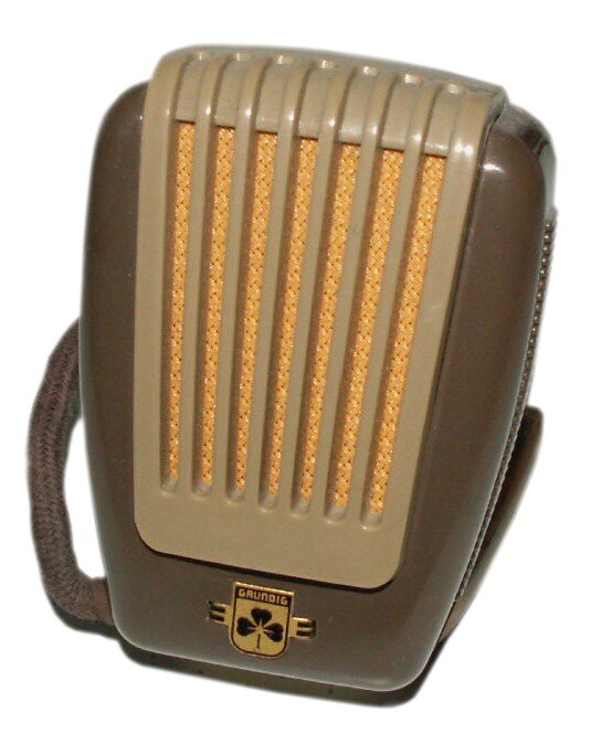 Na zdjęciu widoczny jest mikrofon węglowy, w pozycji pionowej, w ujęciu trzy czwarte. Ma kształt brązowego prostokąta z zaokrąglonymi narożnikami, lekko rozszerzający się ku górze. Pośrodku znajduje się jasnobrązowy panel w kształcie zbliżonym do prostokąta, rozszerzający się ku górze, z sześcioma pionowymi liniami, pomiędzy którymi widoczna jest złota membrana, wykonana z plecionki cienkich drucików. W dolnej części znajduje się złote logo. Z tyłu mikrofonu, po lewej stronie widoczny jest pasek plecionki w kolorze brązowym.