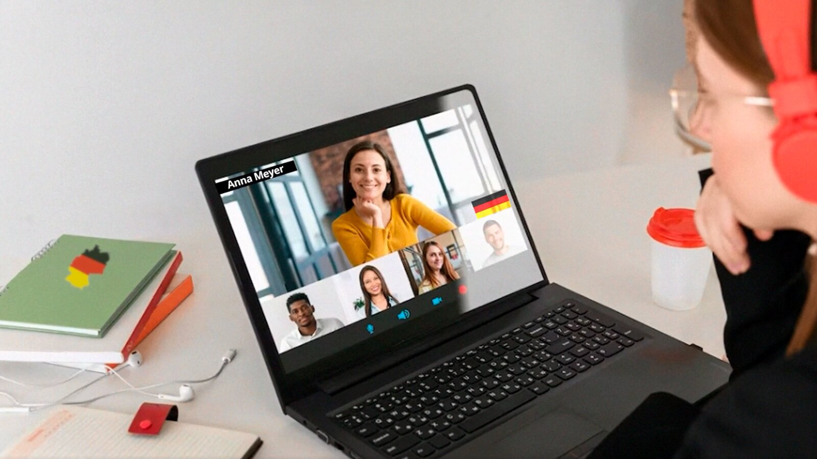   Videoplattformen werden schon seit Langem nicht nur zur Unterhaltung, sondern auch zum Lernen genutzt. Deutschsprachige Filme, Serien, Beiträge oder Präsentationen eignen sich zur gezielten Weiterbildung des Hörverständnisses und zur Erweiterung des Wortschatzes. Anhand typischer Alltagssituationen und Dialoge werden wichtige Redemittel, Fragen, Grammatik, Satzstrukturen und natürlich die Aussprache geübt. Außerdem gibt es immer mehr kreative und attraktive Videokanäle zum Sprachenlernen sowie zur Landeskunde, die man abonnieren kann.
7. Mit Videos die Sprachkenntnisse verbessern
Videoplattformen werden schon seit Langem nicht nur zur Unterhaltung, sondern auch zum Lernen genutzt. Deutschsprachige Filme, Serien, Beiträge oder Präsentationen eignen sich zur gezielten Weiterbildung des Hörverstehens und zur Erweiterung des Wortschatzes. Anhand typischer Alltagssituationen und Dialoge werden wichtige Redemittel, Fragen, Grammatik, Satzstrukturen und natürlich die Aussprache geübt.
Opis: na ilustracji widoczna jest kobieta siedząca przy biurku, na którym stoi otwarty laptop. Na jego ekranie widoczny jest ekran wideokonferencji z pięcioma uczestnikami.
