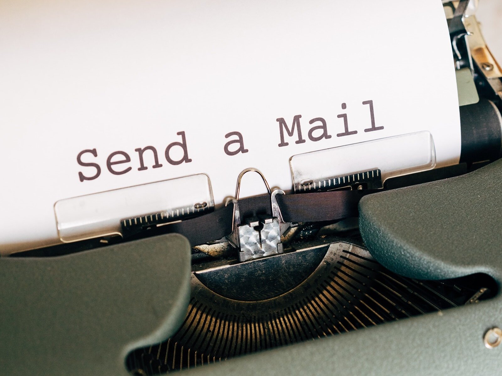 Zdjęcie przedstawia górny fragment maszyny do pisania, tzw. wózek, w który włożona jest biała kartka z napisem w języku angielski: Send a Mail.