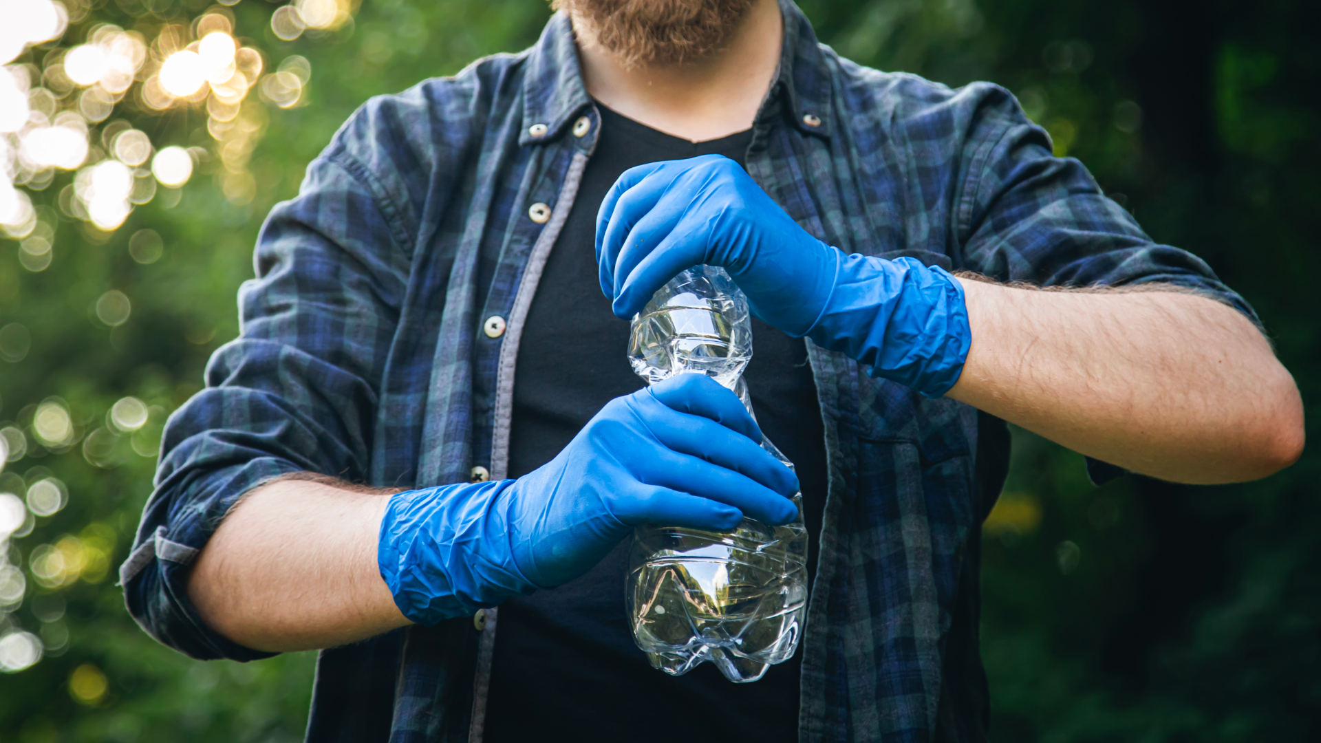 Zdjęcie przedstawia mężczyznę, który zgniata plastikową butelkę. Niewidoczna jest twarz mężczyzny.
