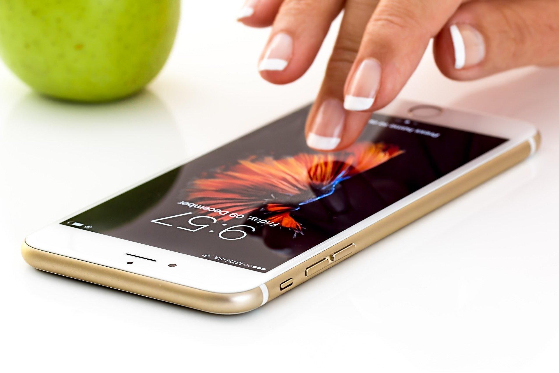 Na ilustracji uwidoczniono ekran iPhone' a, nad którym unosi się kobieca dłoń.