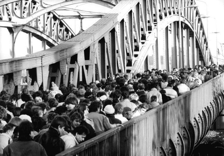 Tłum obywateli NRD na moście przed przejściem granicznym, 18 listopada 1989 Źródło: Robert Roeske, Tłum obywateli NRD na moście przed przejściem granicznym, 18 listopada 1989, Fotografia, Bundesarchiv, licencja: CC BY-SA 3.0.
