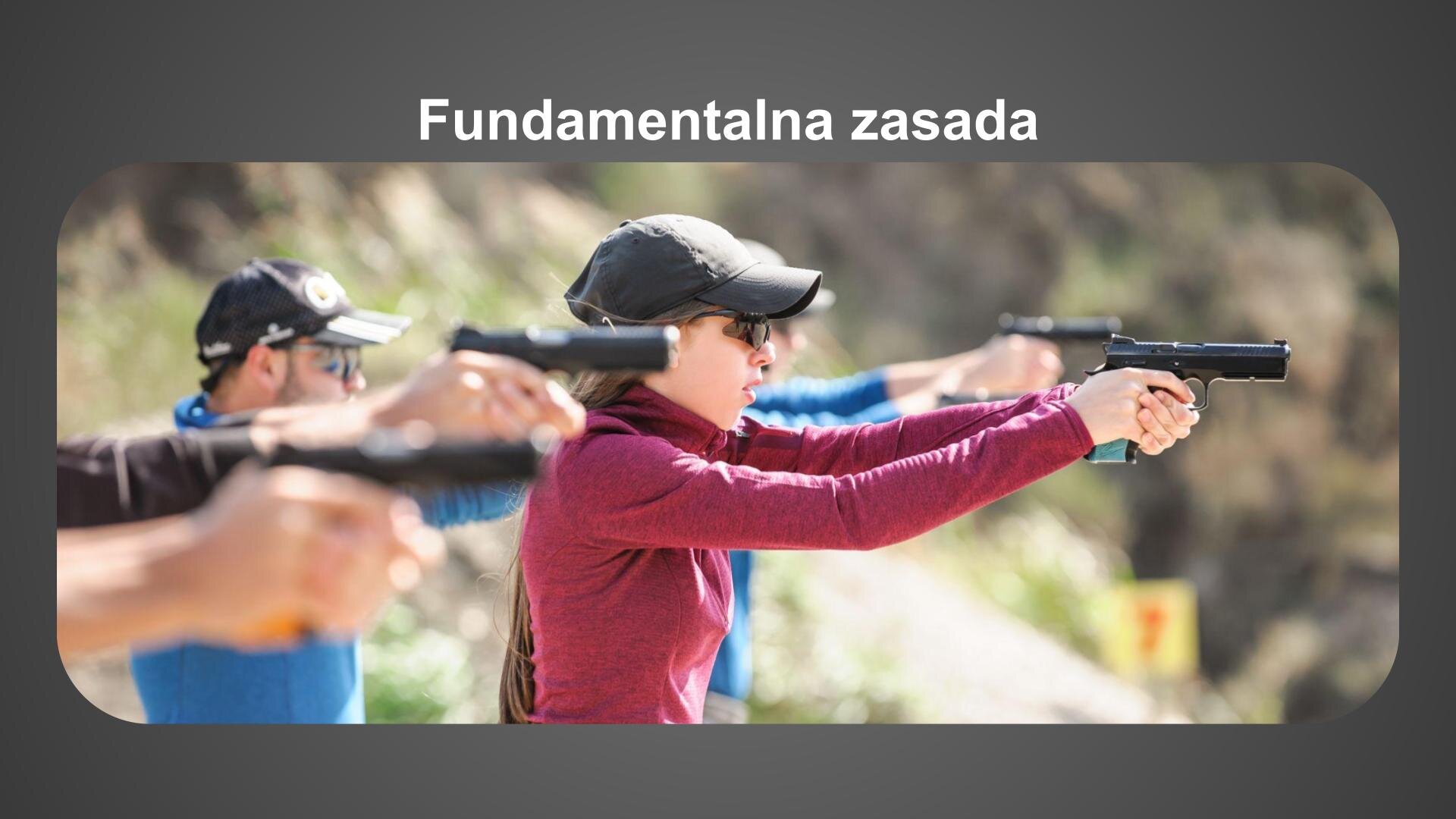 Szara plansza. U góry biały napis: „Fundamentalna zasada”. Poniżej zdjęcie przedstawiające grupę osób, które trzymają w wyprostowanych dłoniach pistolety. Wszyscy mają na głowach ciemne czapki z daszkiem i okulary przeciwsłoneczne. W tle piaskowe wzgórza, zielone krzewy i drzewa.