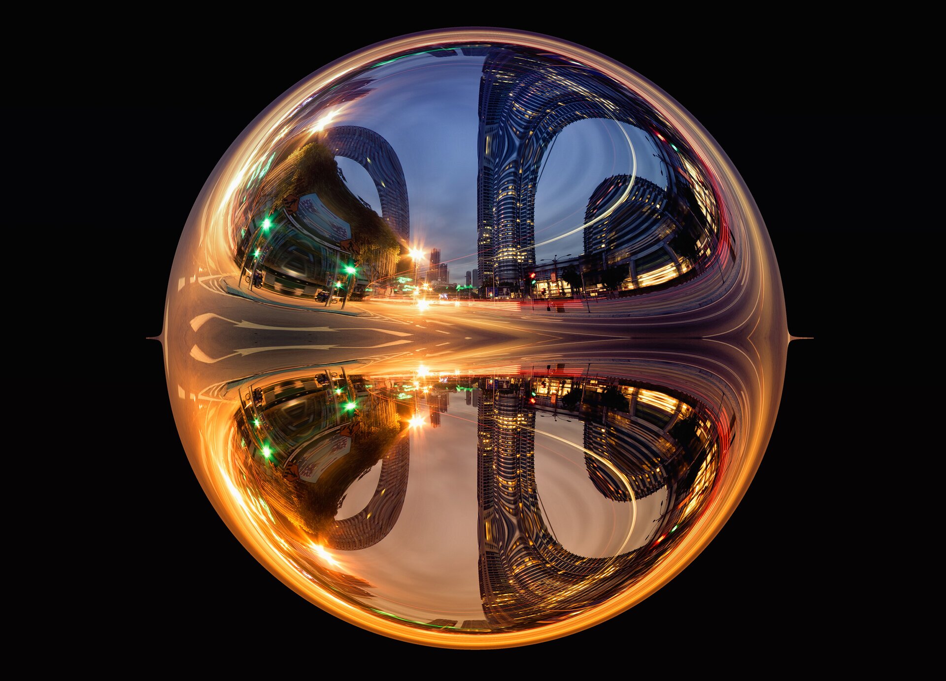 Zdjęcie przedstawia podświetloną kulę, w której widoczny jest zniekształcony fragment zabudowy dużego miasta. W poziomie przez środek kuli biegnie świetlisty, złoty pas ulicy, który rozdziela się i biegnie w górę i w dół. W górnej części widoczne są zniekształcone wieżowce na tle jasnogranatowego nieba, natomiast na dole kuli widoczne jest lustrzane odbicie wieżowców na tle szarego nieba..
