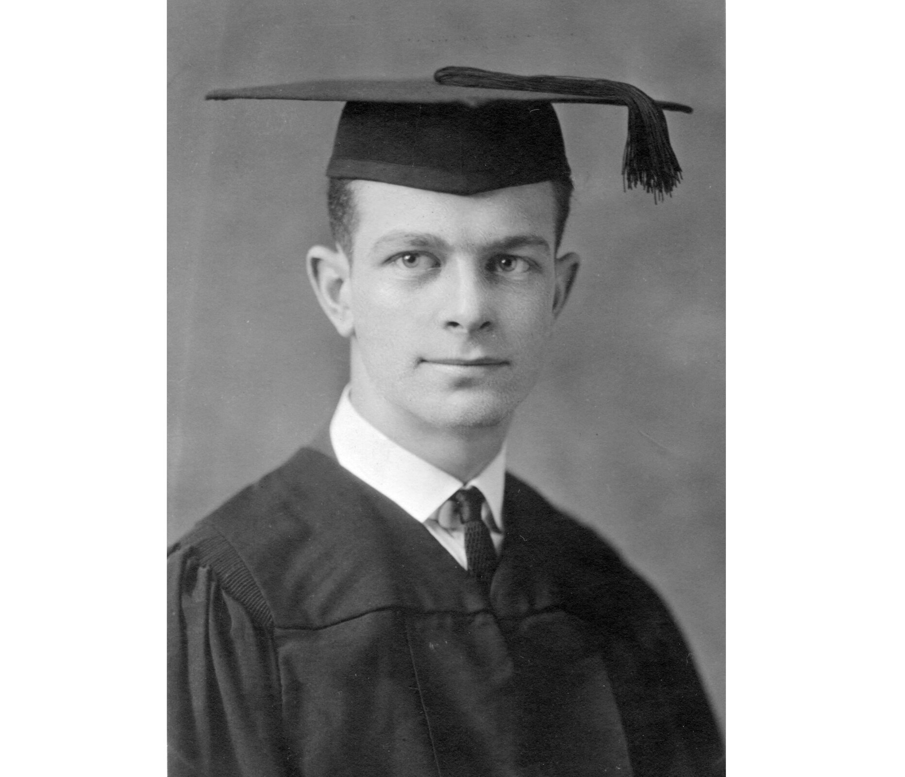 Czarno—białe zdjęcie przedstawia młodego Linusa Carla Paulinga. Jest on ubrany w białą koszulę, czarny krawat i togę. Na głowie ma akademicki beret. Tło zdjęcia jest szare.