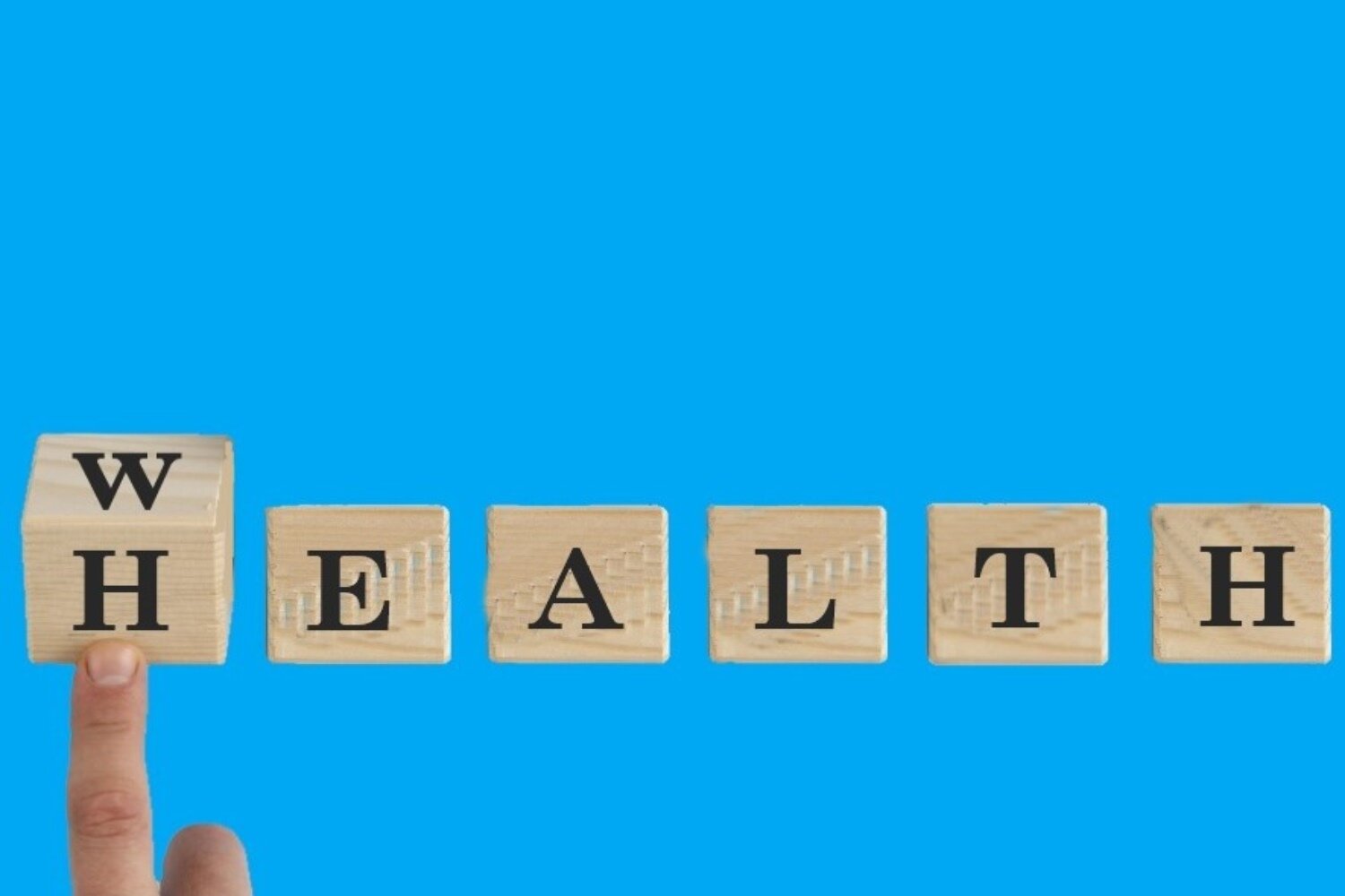 Zdjęcie przedstawia sześć drewnianych kostek ułożonych w rzędzie na niebieskim tle. Na każdej widoczna jest inna litera. Na pierwszej kostce, która jest lekko przekręcona przez dotykający ją palec, widoczne są dwie litery: W i H. Jeśli wybierzemy literę W na pierwszej kostce, to z pozostałymi literami stworzą słowo: WEALTH. Jeśli wybierzemy literę H na pierwszej kostce, to z pozostałymi literami stworzą słowo: HEALTH.