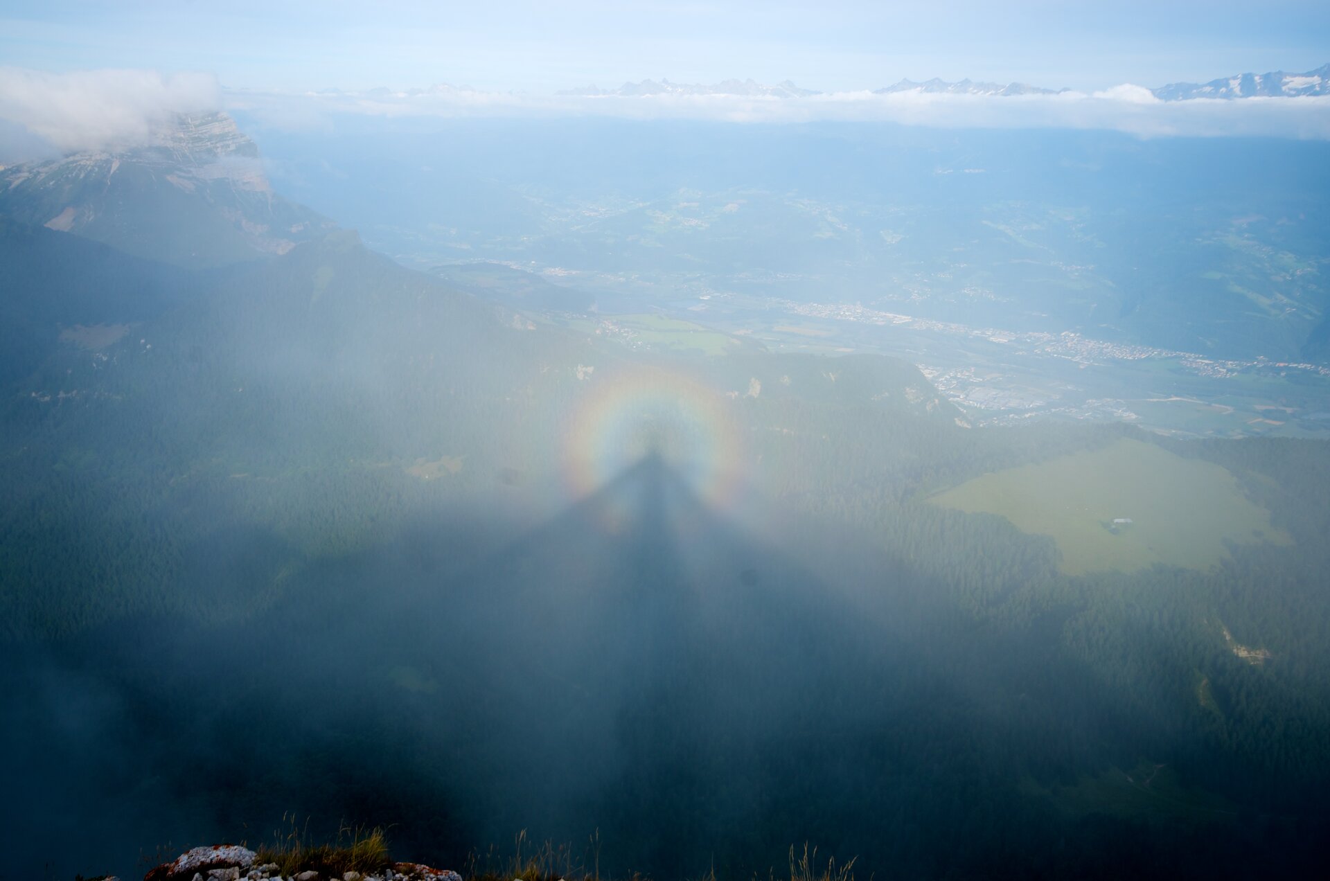Fotografia prezentuje zjawisko optyczne spotykane w górach, nazwane Widmem BrockenuNa fotografii widoczny cień osoby na chmurze, która znajduje się poniżej obserwatora. Cień otoczony jest tęczową obwódką zwaną glorią.