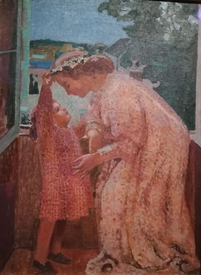 Ilustracja przedstawia fotografię obrazu, na którym znajdują się dwie postaci. W kadrze pierwszy plan w całości wypełniony jest sylwetkami: kobiety i dziecka. Kobieta jest ujęta z profilu i nachyla się nad dzieckiem, które sięga do jej kapelusza. W oddali, przez okno widoczne są fragmenty drzewa i budynku.