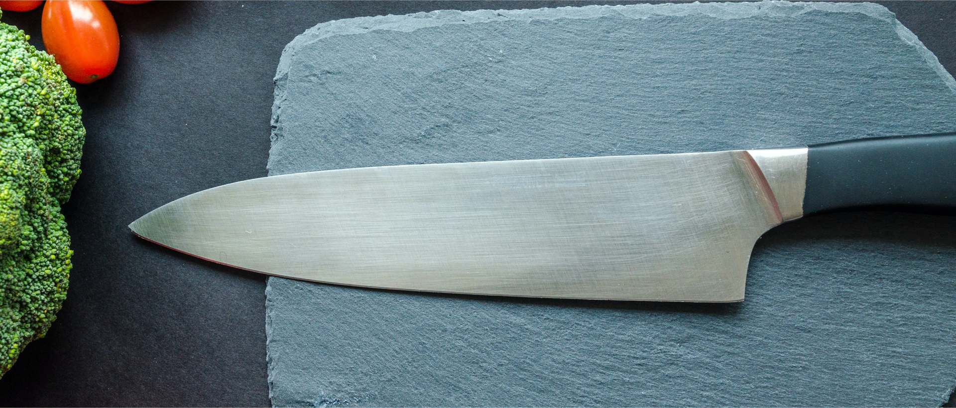 Zdjęcie przedstawia nóż kuchenny leżący na kamiennej desce.