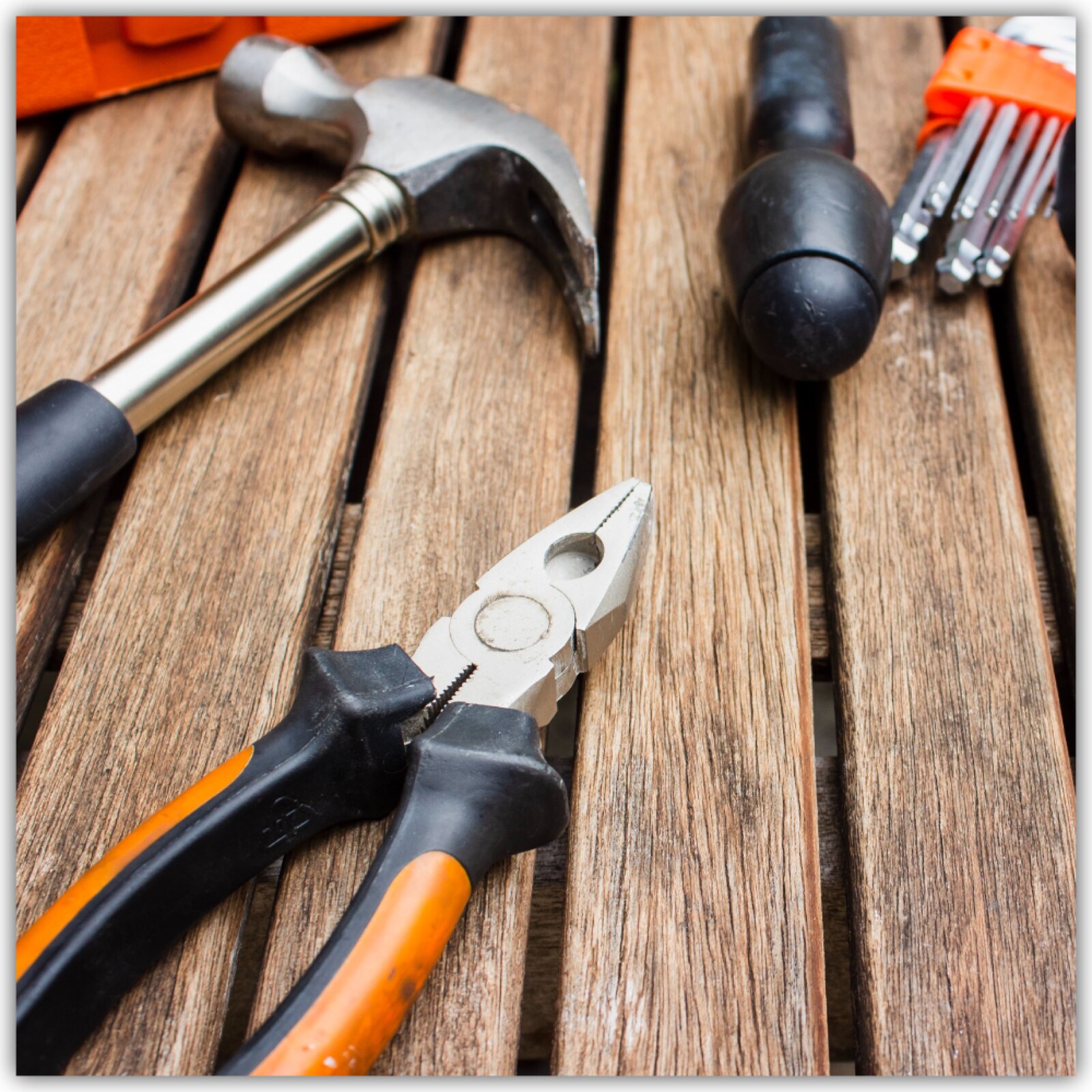 Na stole leżą narzędzia takie jak młotek, kombinerki, śrubokręt.