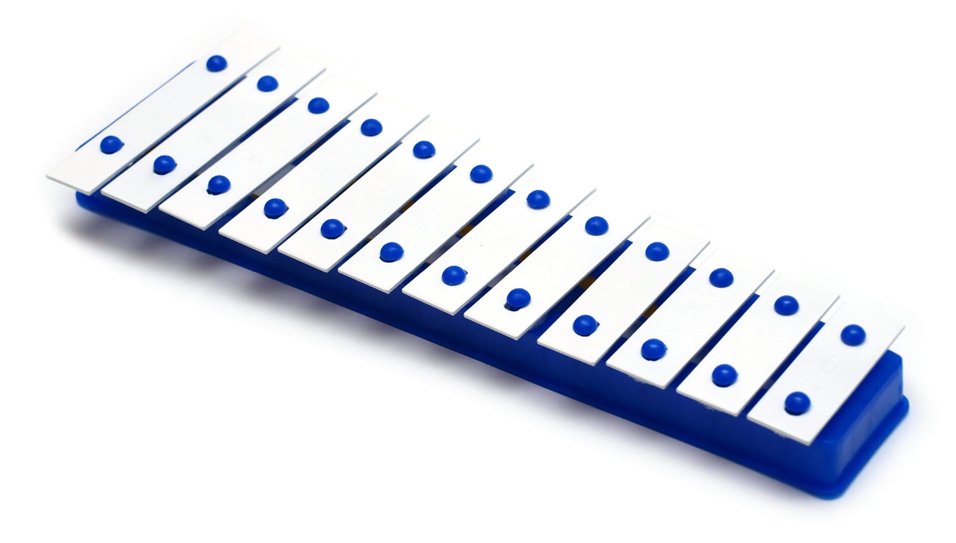 Fotografia przedstawia dzwonki diatoniczne. Instrument składa się z wielu białych sztabek o różnej długości ułożonych jedna przy drugiej. Od najdłuższych z lewej strony do najkrótszych z prawej. Każda sztabka przymocowana jest do niebieskiej podstawy za pomocą dwóch niebieskich elementów. Tło ilustracji jest białe.