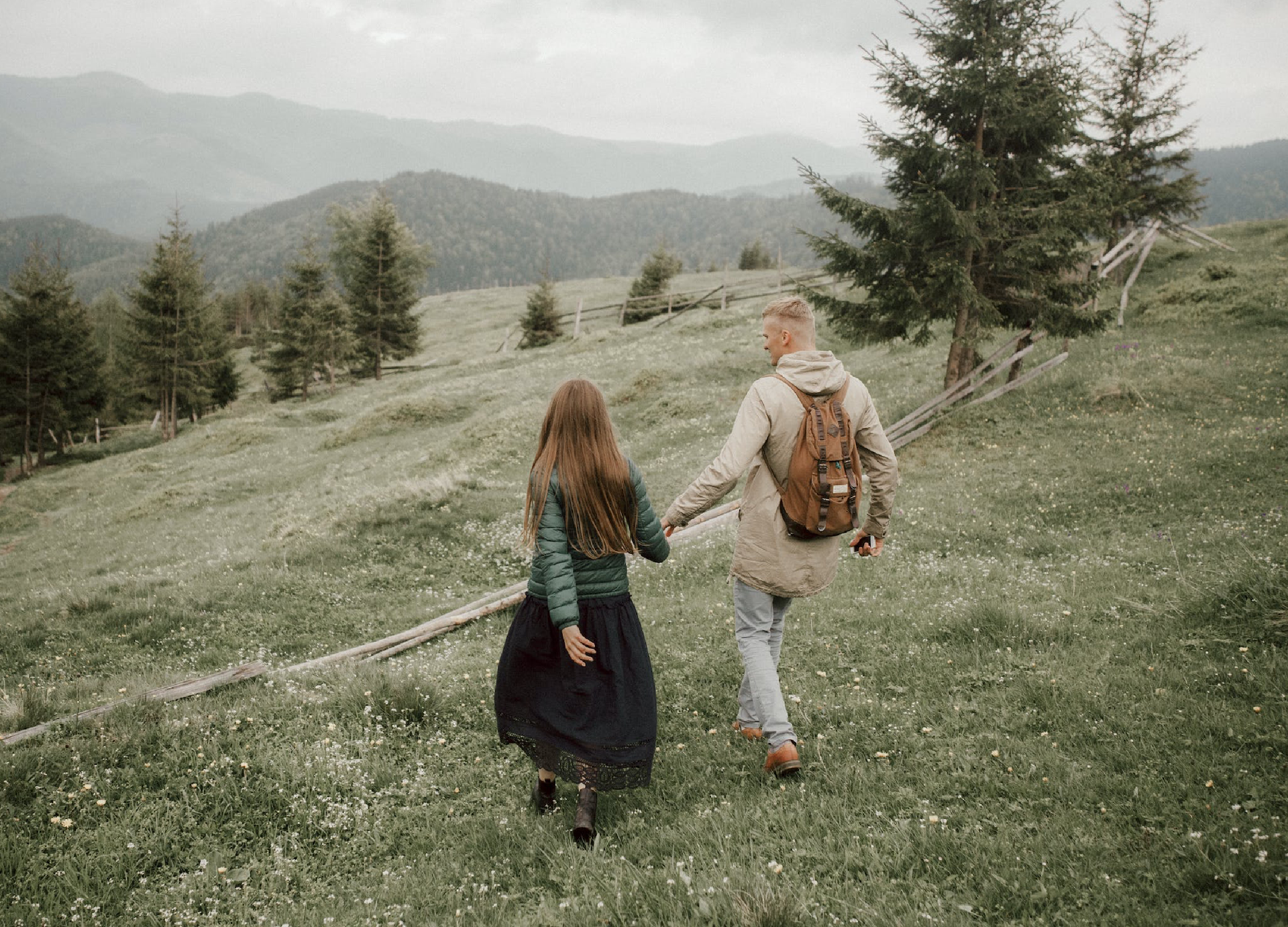 Zdjęcie przedstwia kobietę i mężczyznę schodzących porośniętym trawą zboczem.