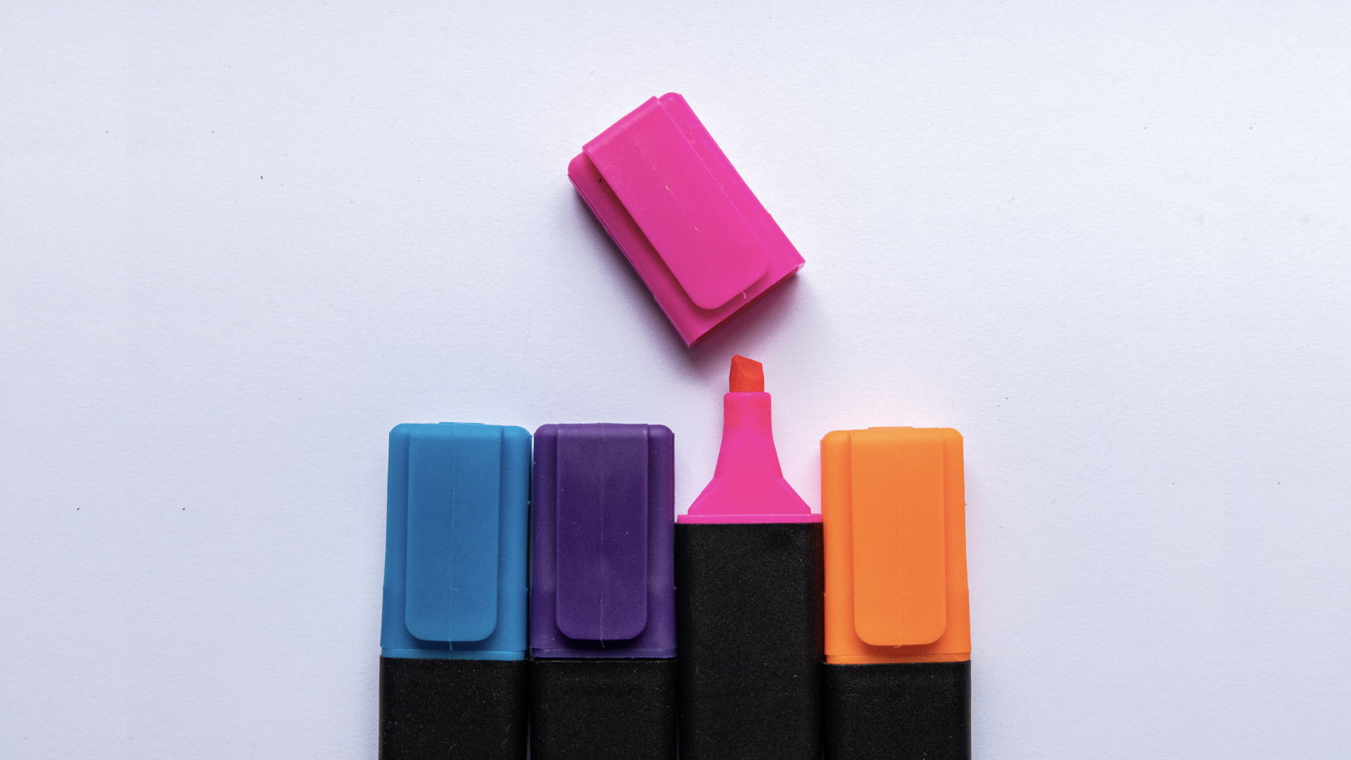 Zdjęcie przedstawia cztery kolorowe zakreślacze, każdy w innym kolorze. Zakreślacze leżą równo jeden przy drugim. Jeden z nich jest otwarty.